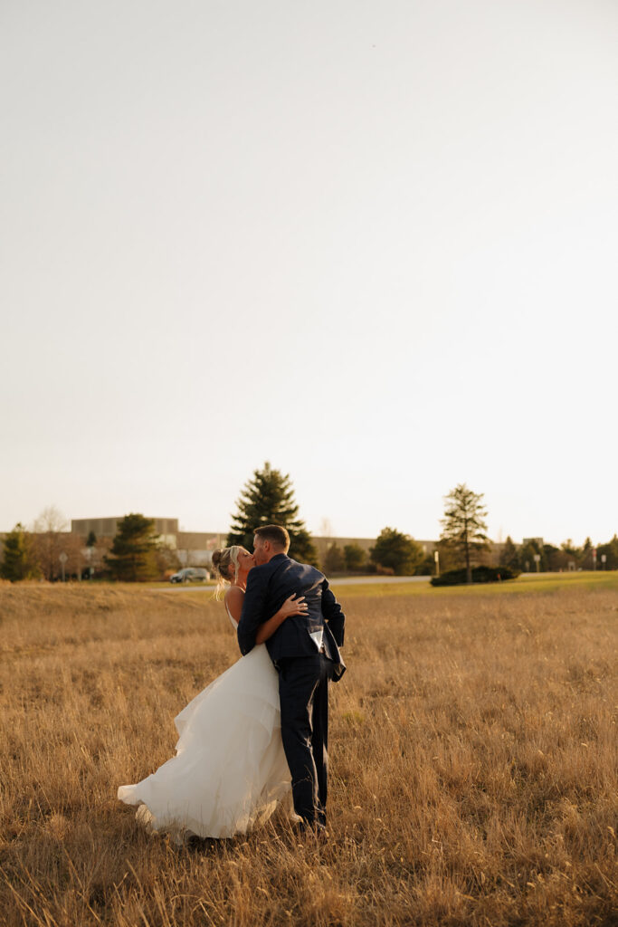 Bride and groom share a golden hour kiss in an open field during their Madison Wisconsin wedding.