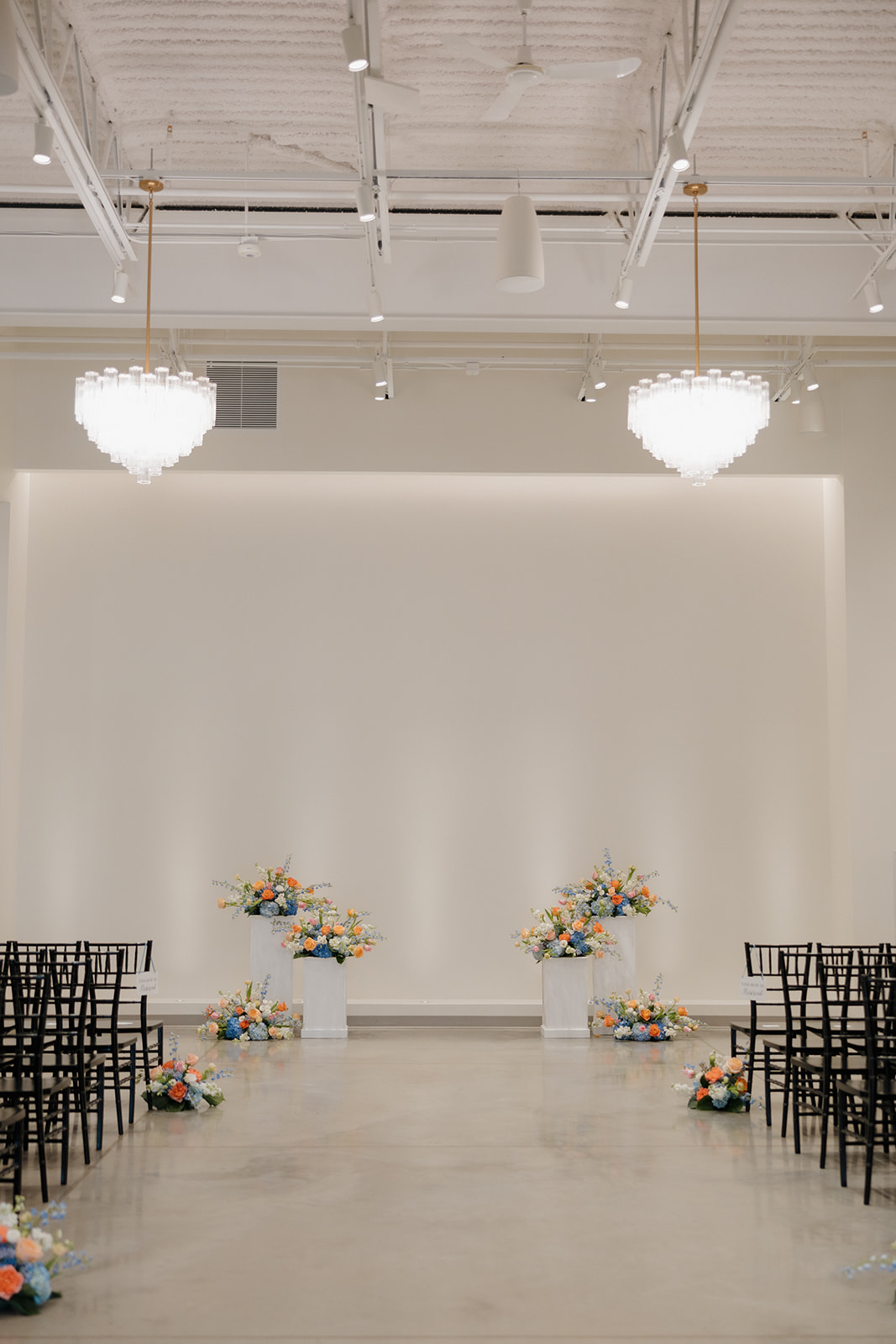 Modern wedding ceremony setup with black chairs and pastel florals at an indoor Madison Wisconsin wedding venue.