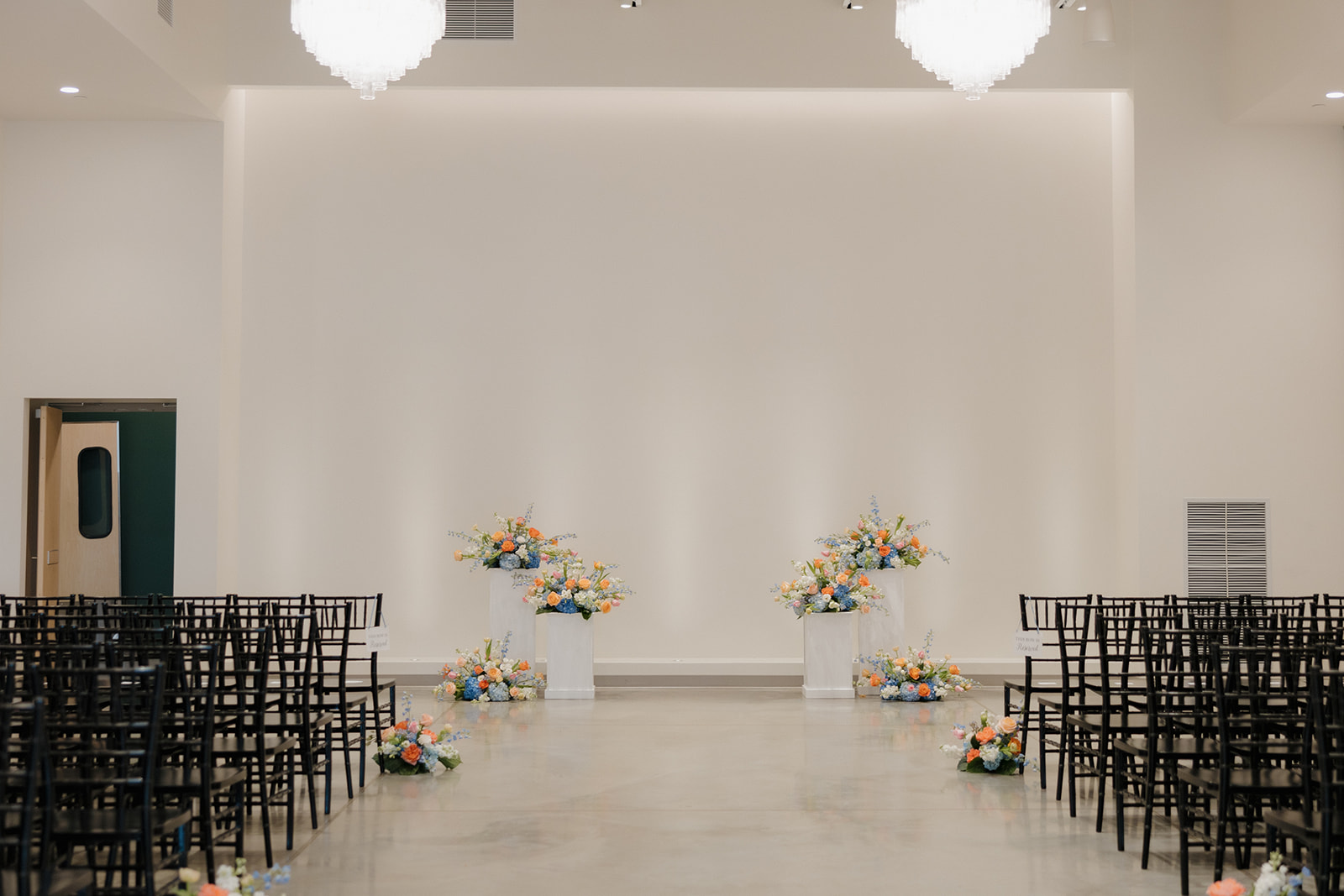 Spacious indoor wedding ceremony setup with black chairs and pastel florals—ready for “I do” in Madison, Wisconsin.