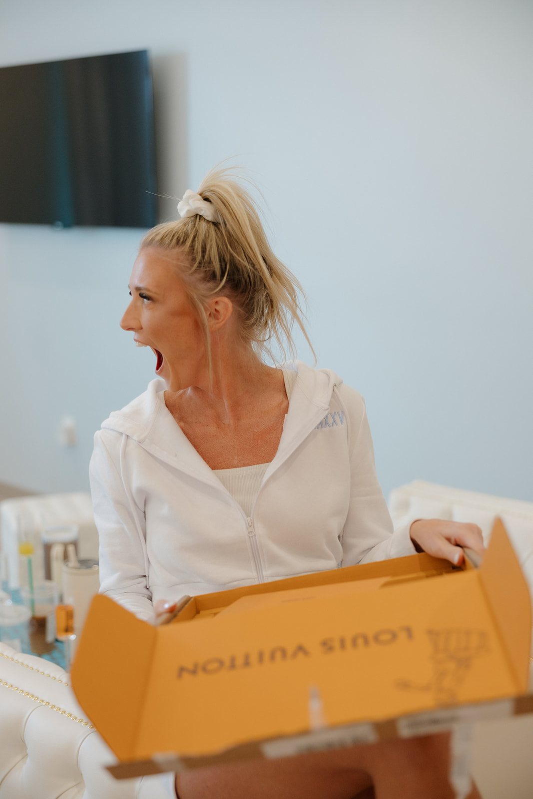 Bride laughs with surprise as she opens a Louis Vuitton box while getting ready on the morning of her Madison Wisconsin wedding.