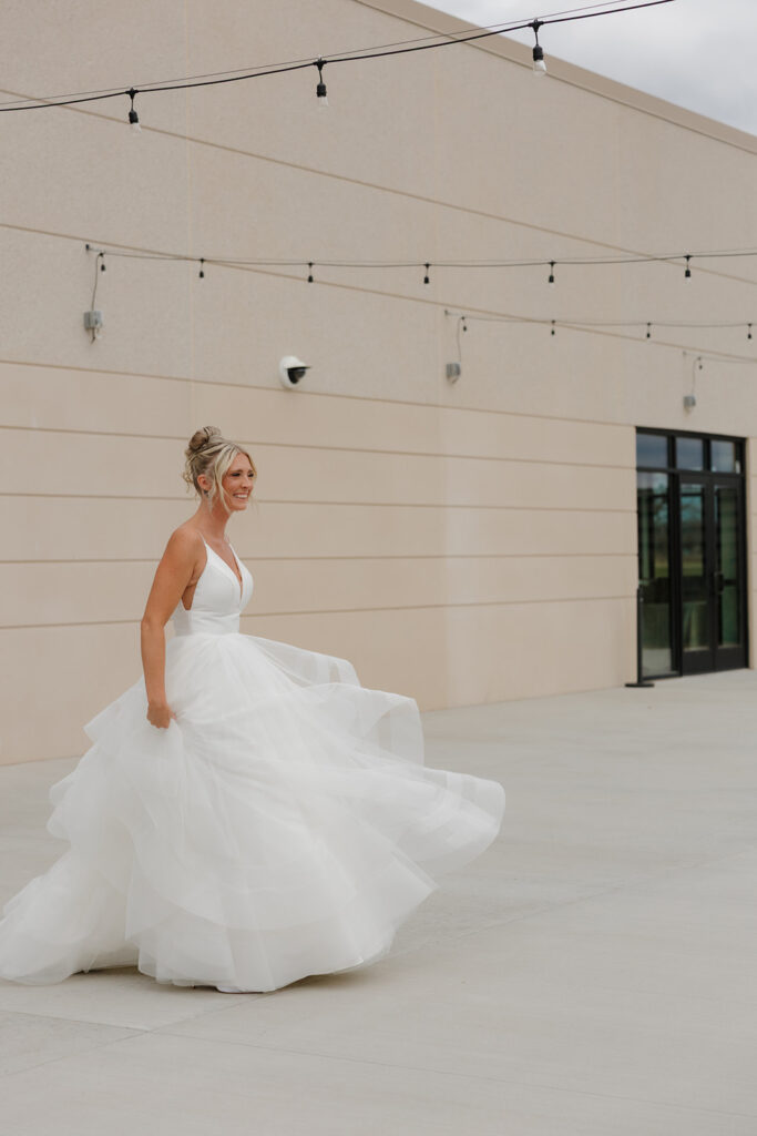 Bride twirls on the patio in her flowy gown, showing off the layers of her dress and her joyful energy.