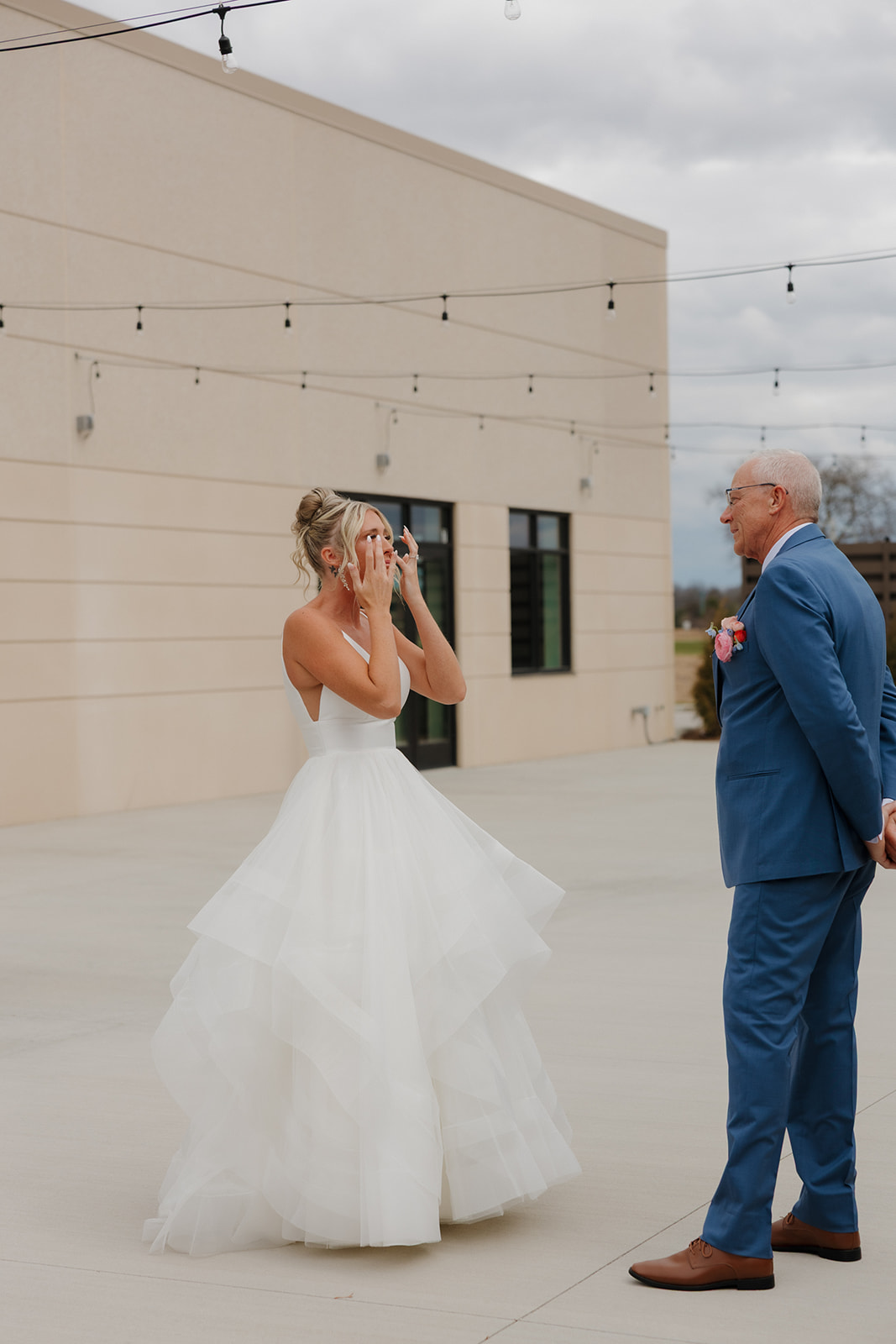 Bride wipes away tears during a touching first look with her father at their Madison Wisconsin wedding