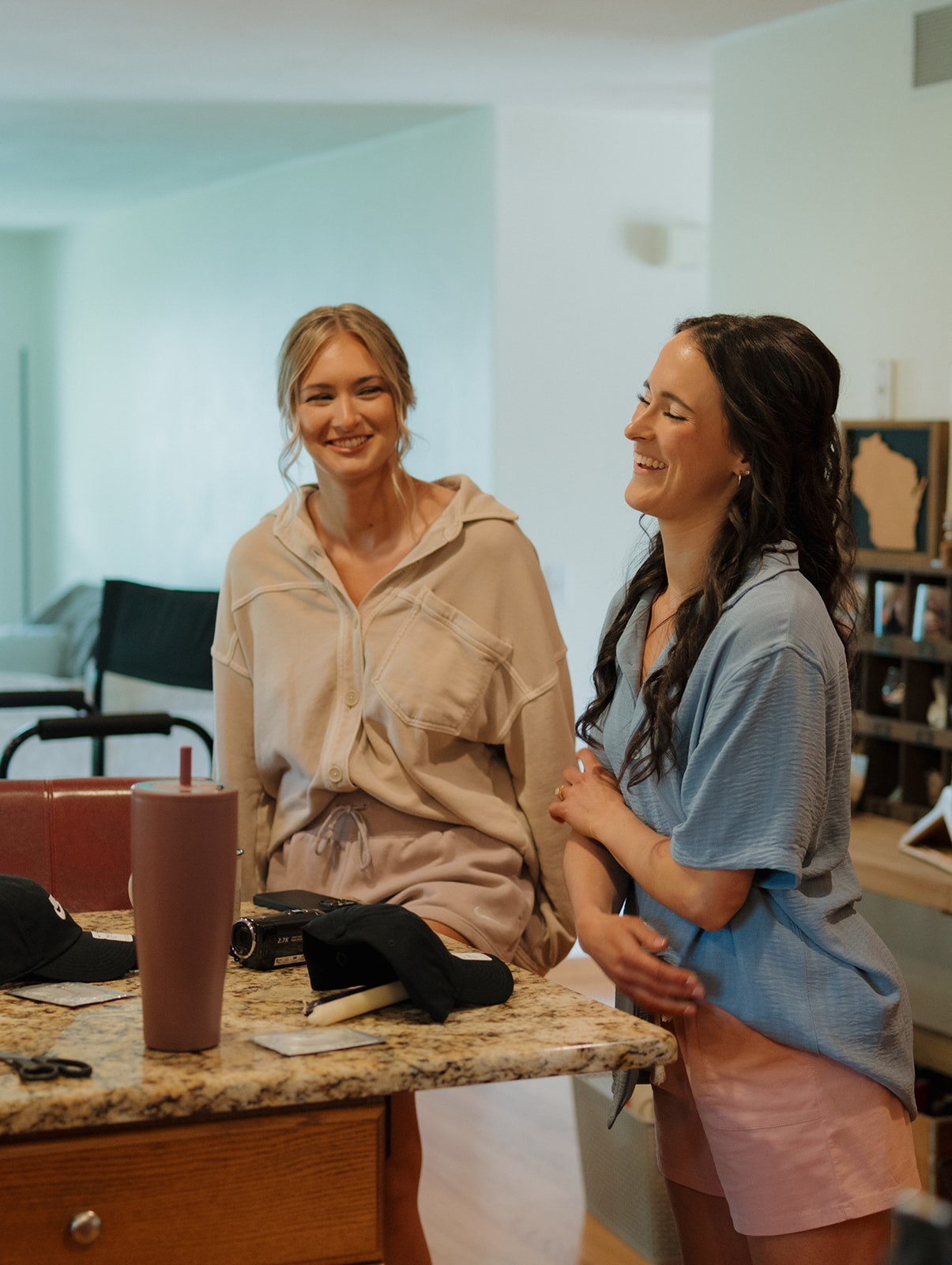 Two bridesmaids laughing and chatting during a relaxed morning getting ready for a country club wedding.