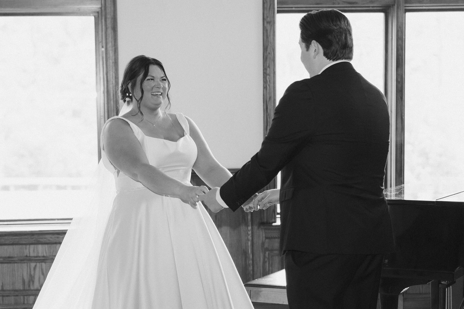 Black and white photo of bride smiling emotionally during a joyful first look moment with the groom at their country club wedding.