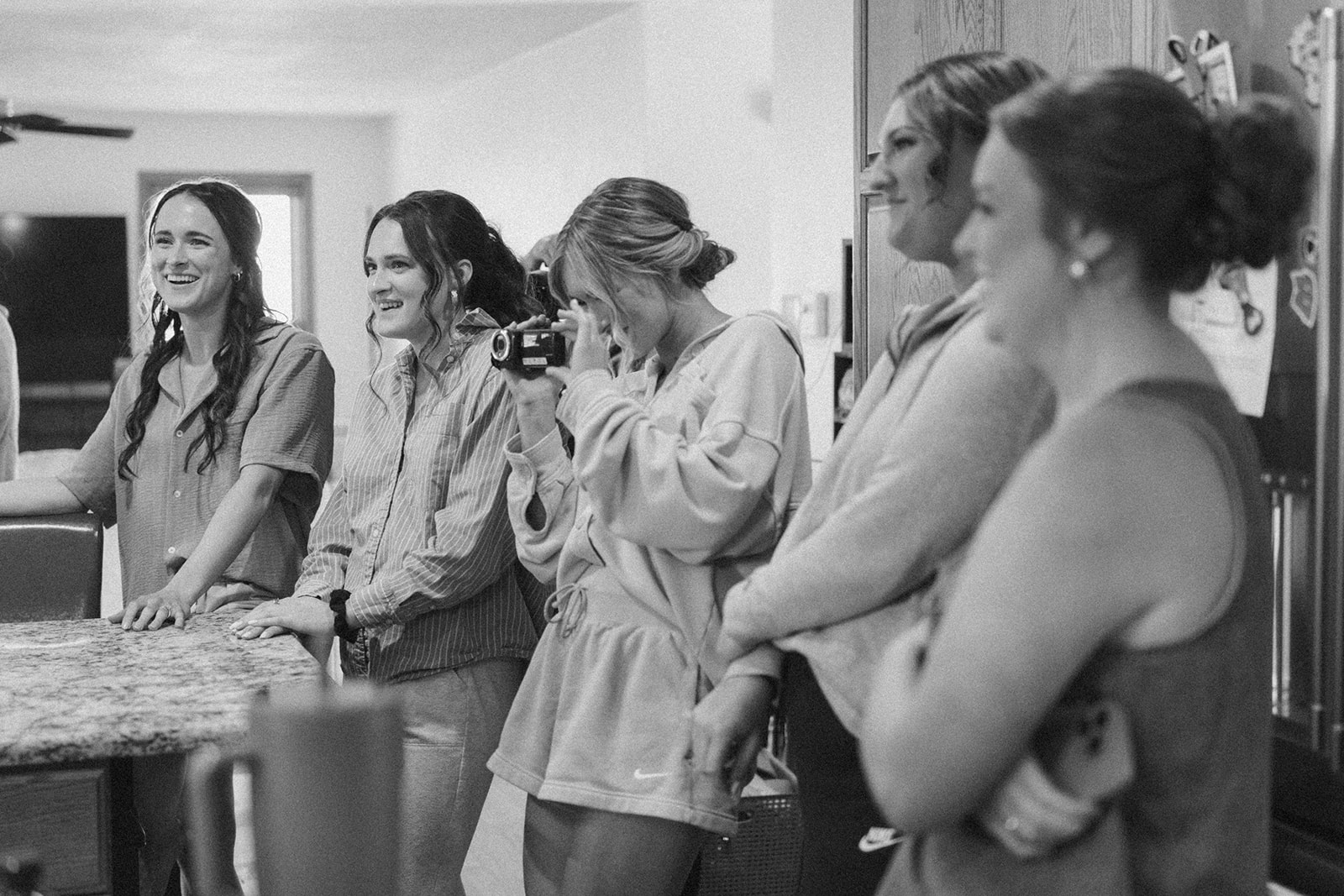 Black and white candid of bridesmaids laughing and filming each other during a joyful country club wedding morning prep.