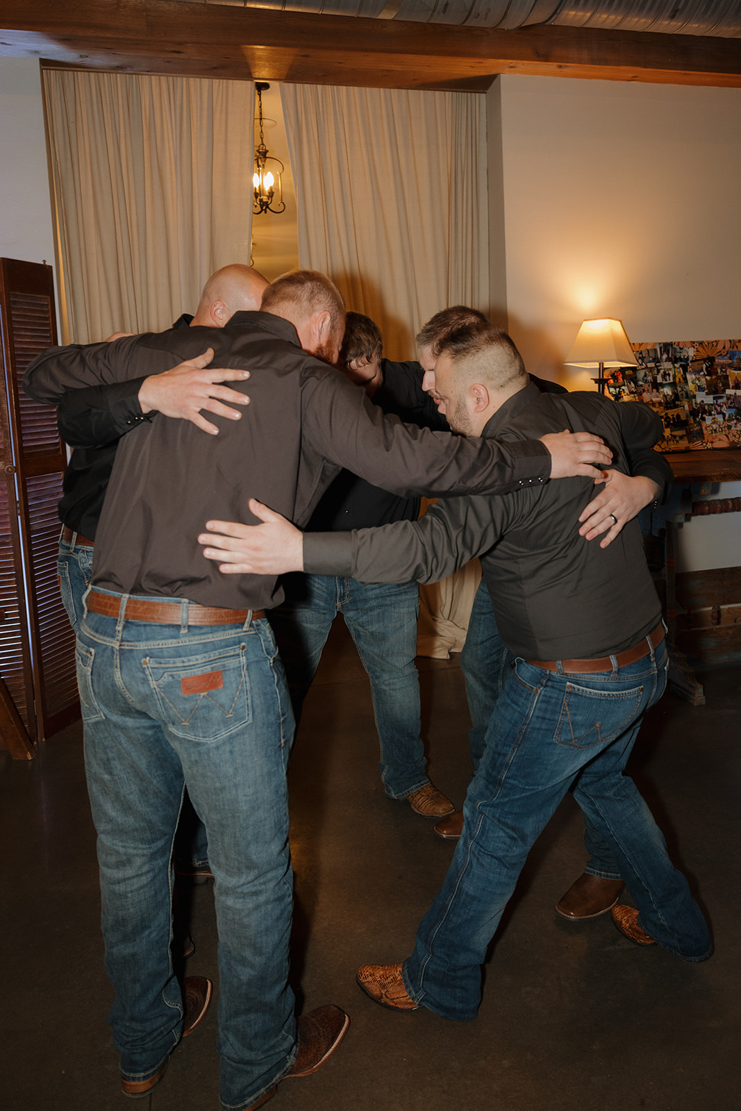 Groomsmen gather in a tight huddle before the reception, sharing a laugh and a quiet moment at this rustic Wisconsin barn wedding.