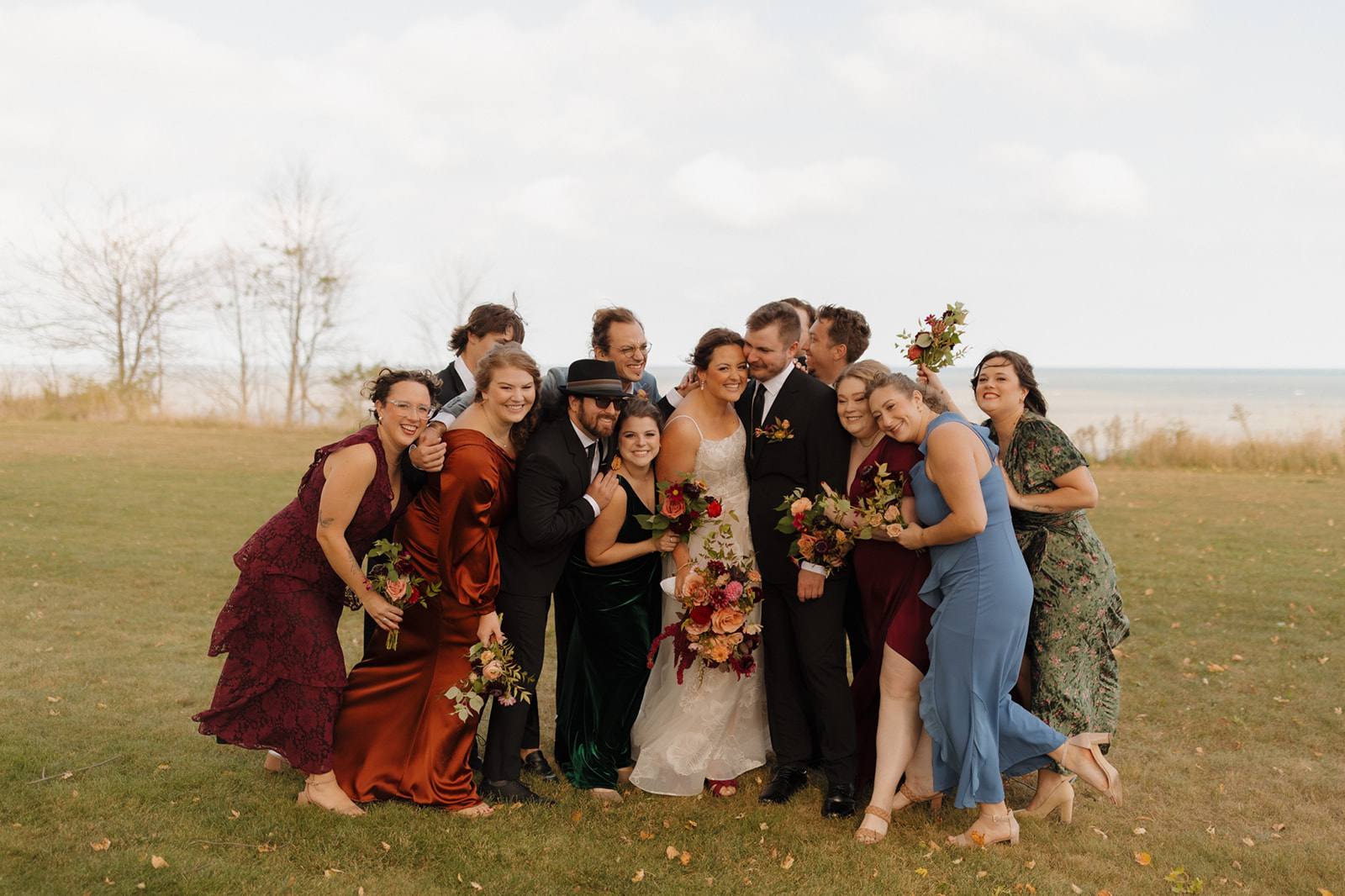 Bride and groom surrounded by joyful wedding party in colorful attire, celebrating lakeside at a vibrant Wisconsin wedding.