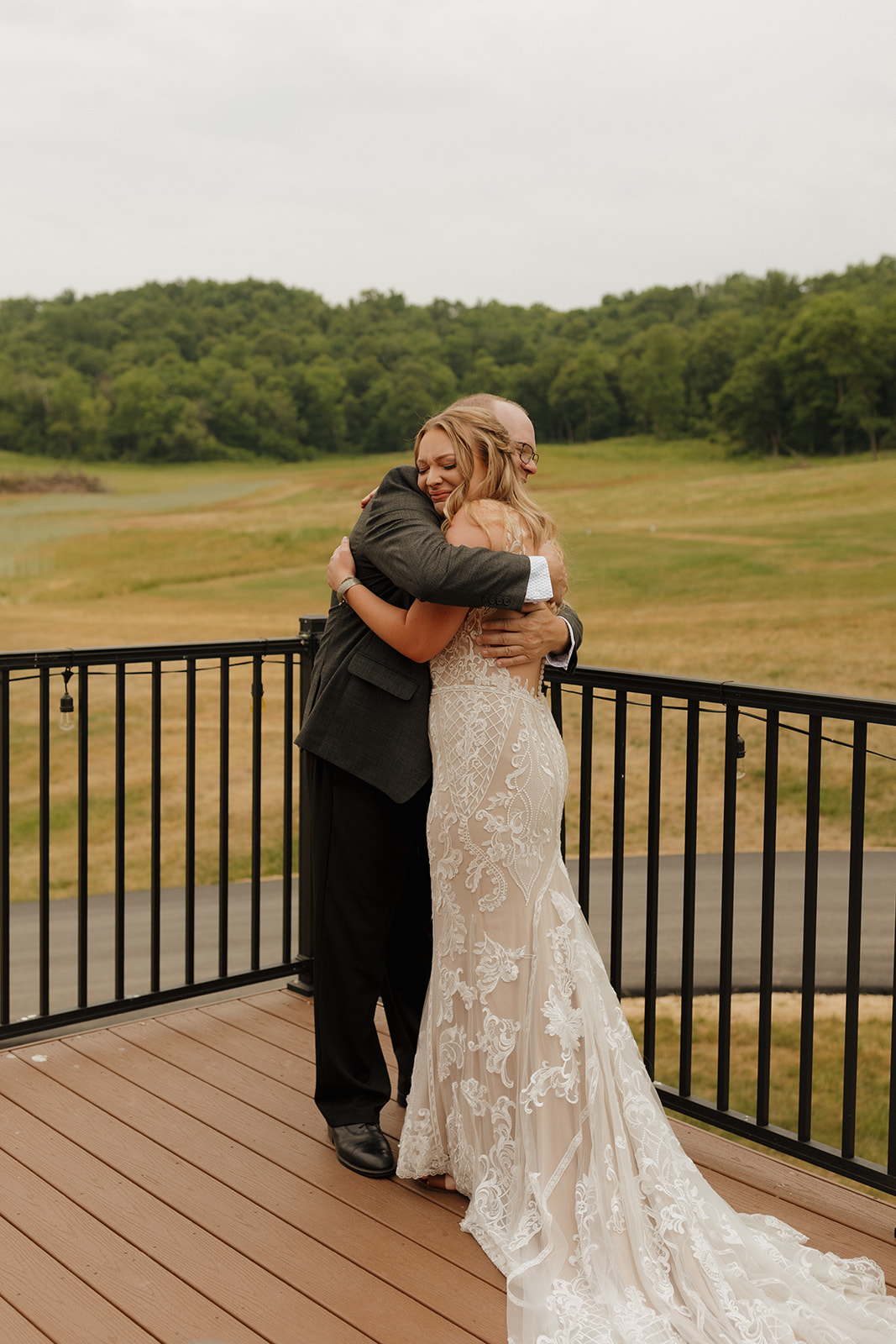 Bride and father share a joyful hug during their emotional first look on a deck overlooking rolling hills before the ceremony.
