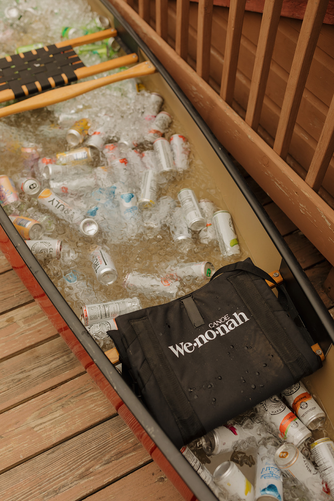 A canoe filled with ice and assorted drinks, serving as a playful DIY cooler setup for a laid-back backyard wedding celebration.