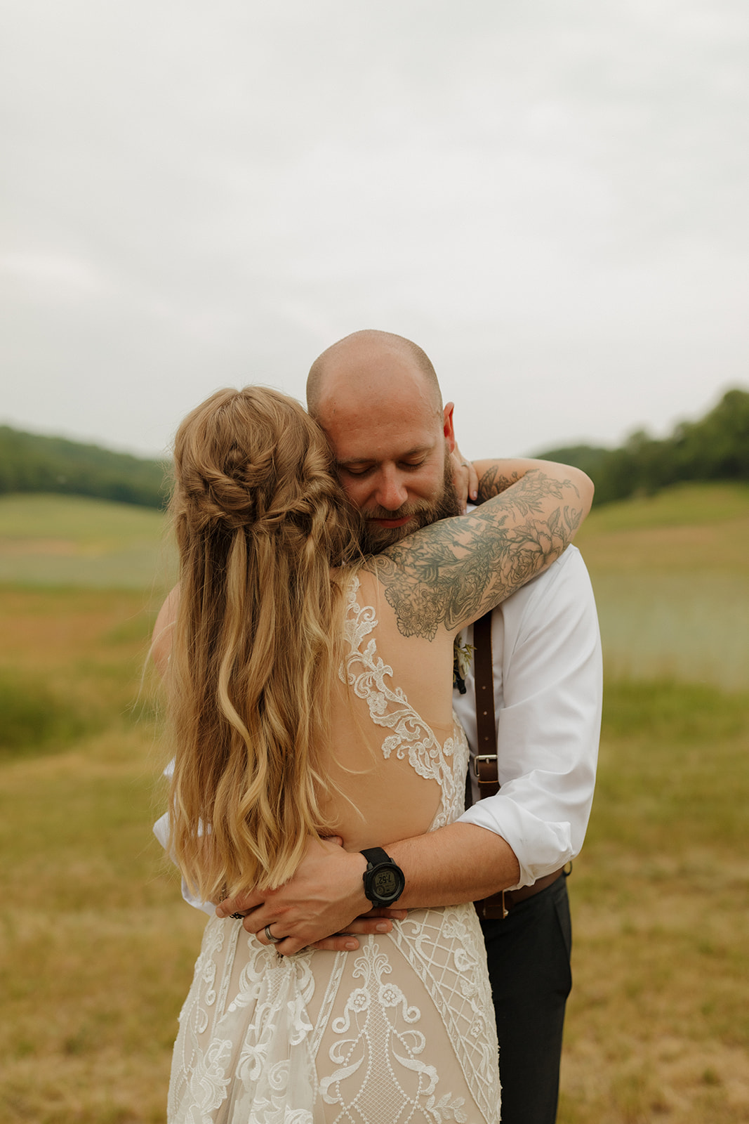 Bride and groom hold each other tight in an emotional embrace after their first look, with golden hills behind them at their backyard wedding.