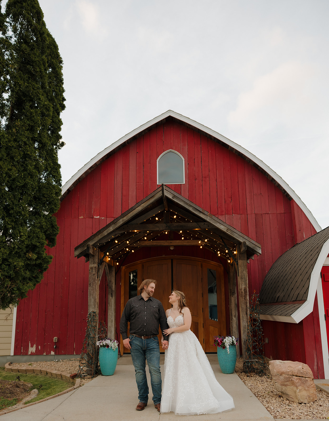 Just married! The couple stands hand in hand in front of a rustic red barn at their Wisconsin barn wedding.