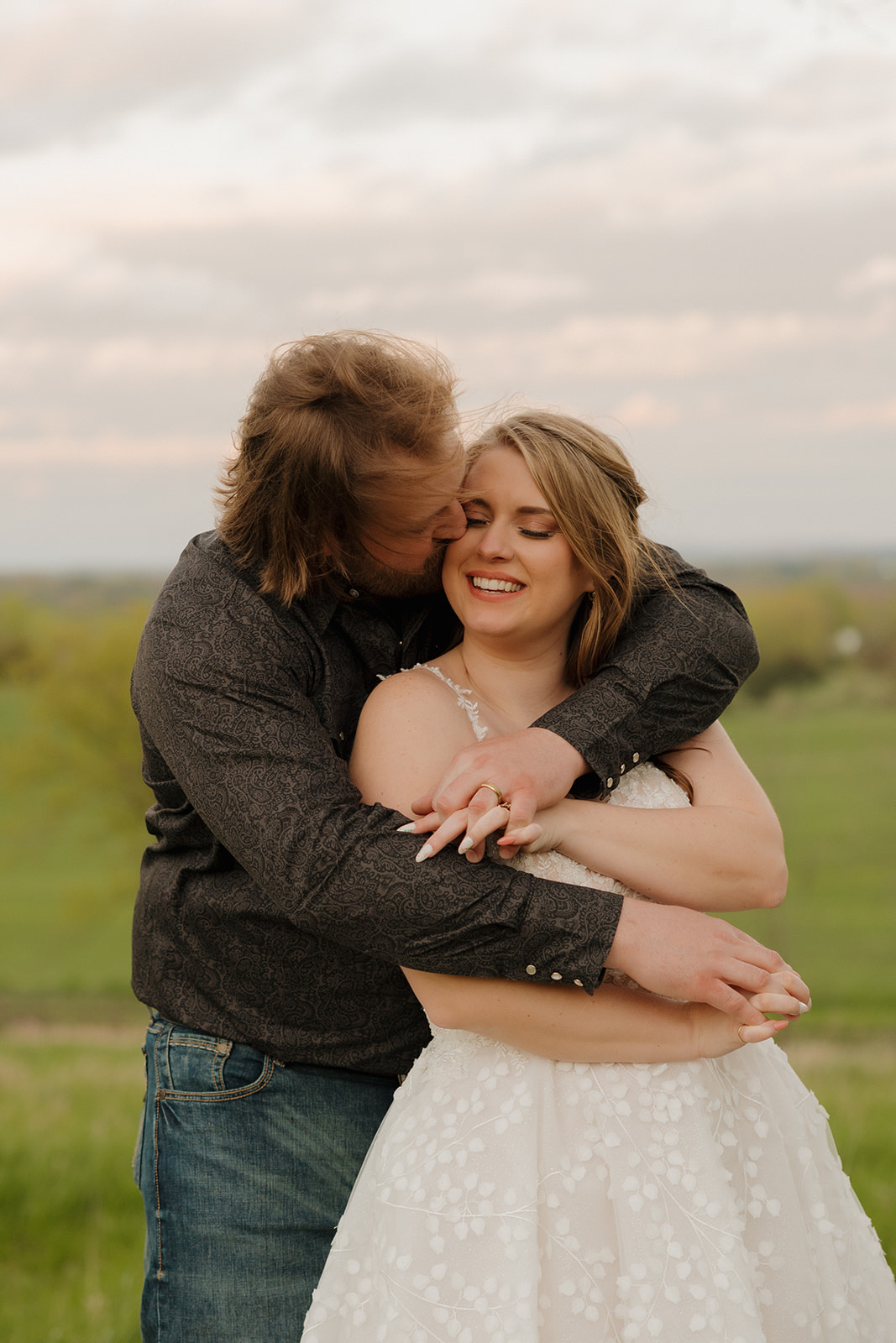 Groom wraps his bride in a warm hug, capturing a candid moment full of joy during their Wisconsin barn wedding.