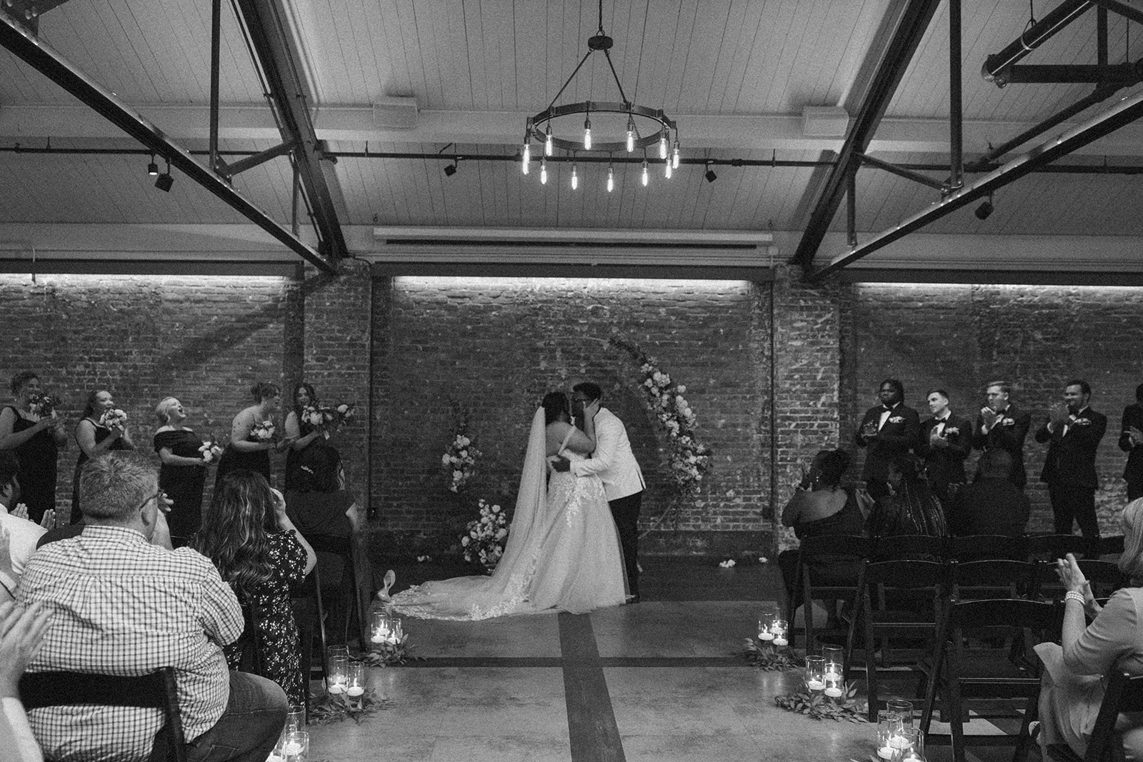 Emotional first kiss as newlyweds at The Gage with friends and family applauding.