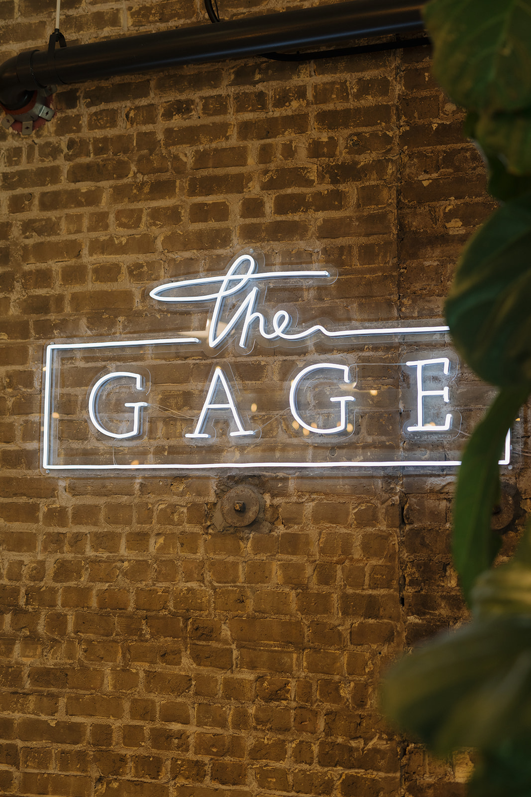 The Gage wedding venue sign glowing against an exposed brick wall in West Allis.