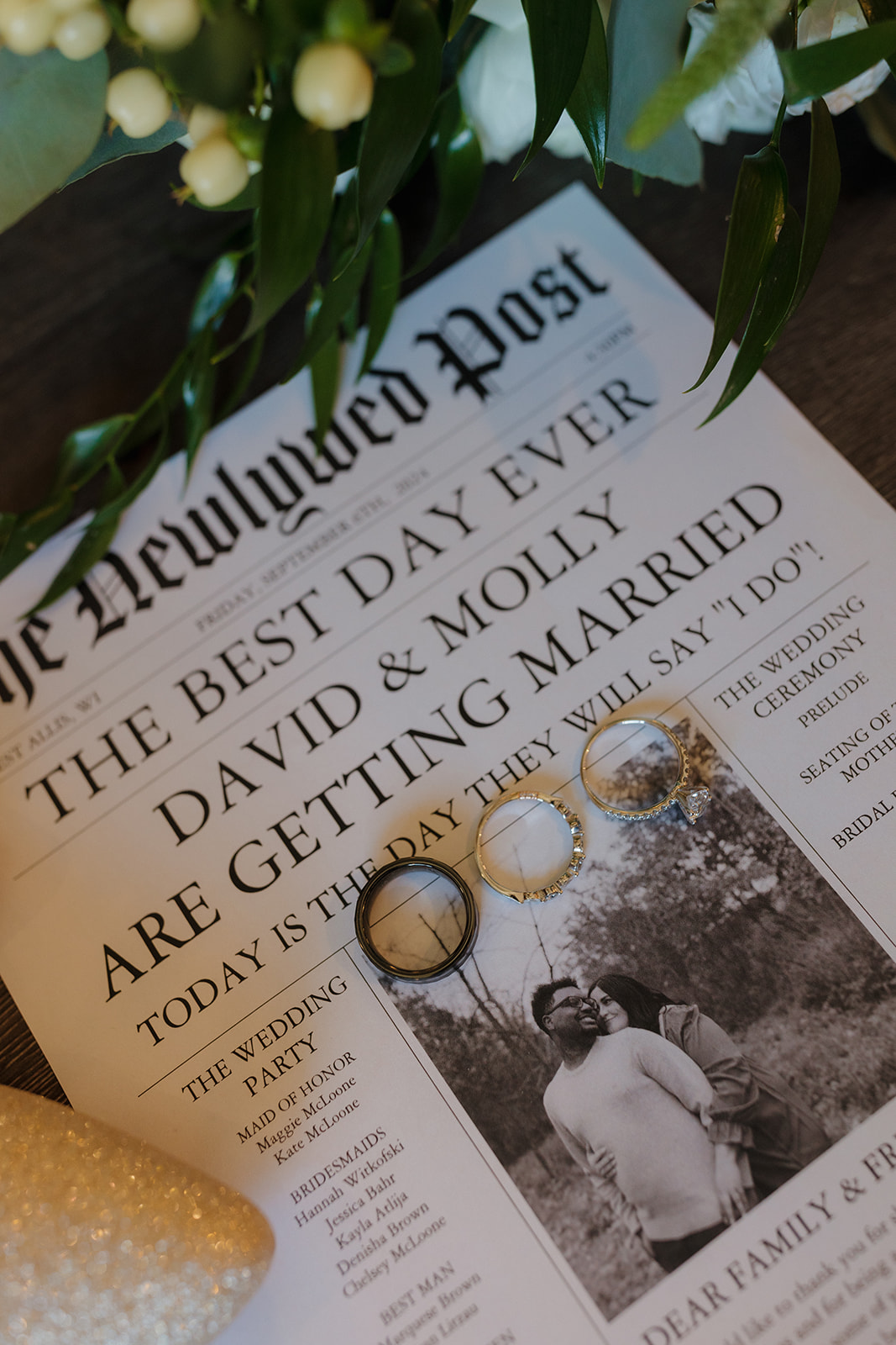 Personalized wedding newspaper with couple’s photo and rings placed on top for detail photography.