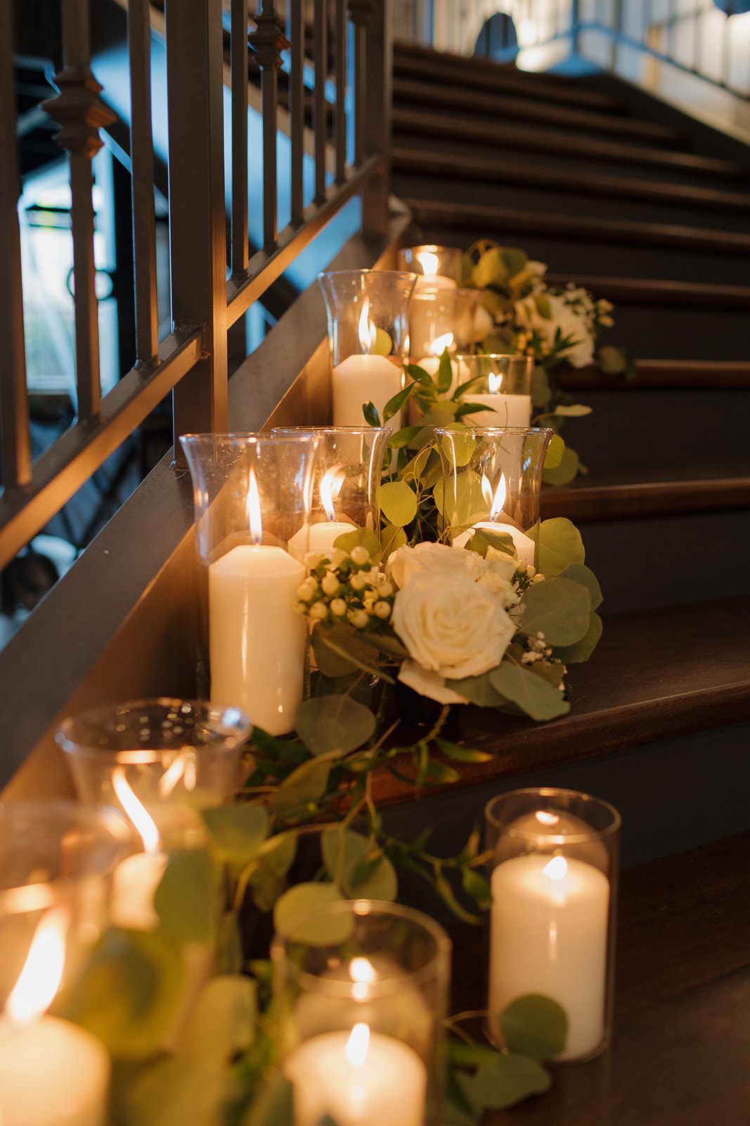 Romantic staircase decor with white roses, greenery, and candlelight at The Gage in Milwaukee.