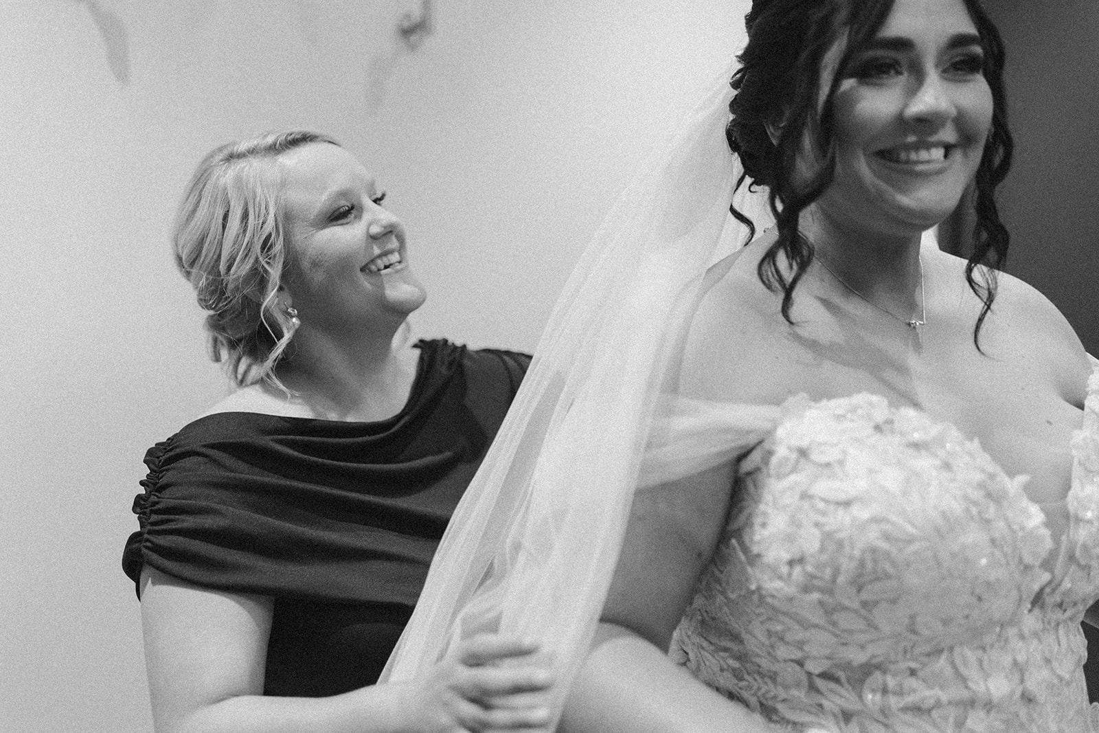 Bridesmaid helps the bride with her veil while getting ready for the ceremony.