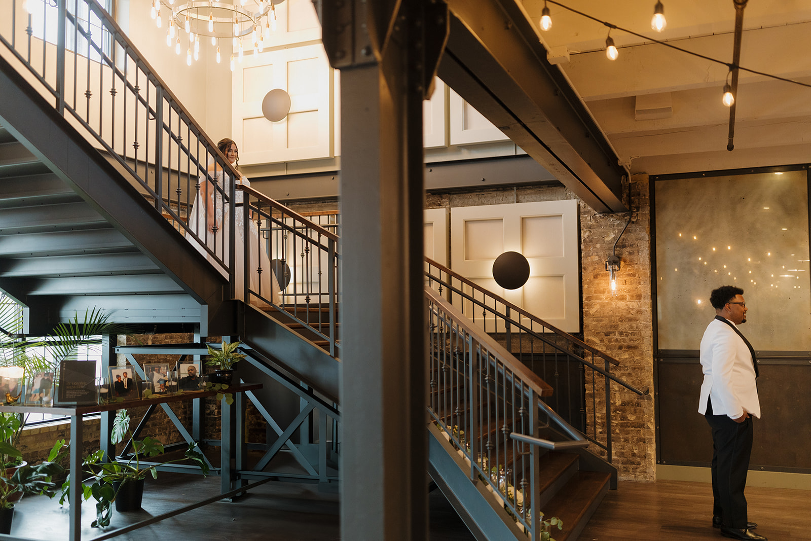 Bride walks down metal staircase toward groom for their first look moment.