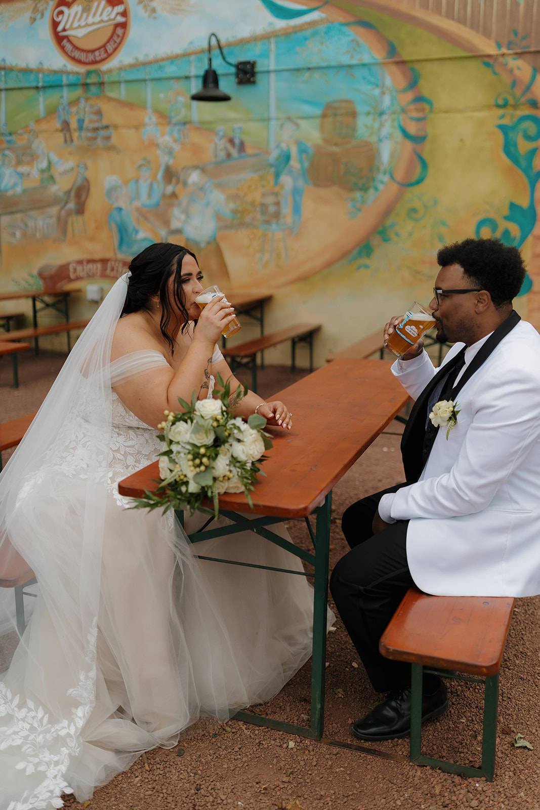 Bride and groom sharing a local beer at South Shore Terrace beer garden during their Milwaukee wedding day.