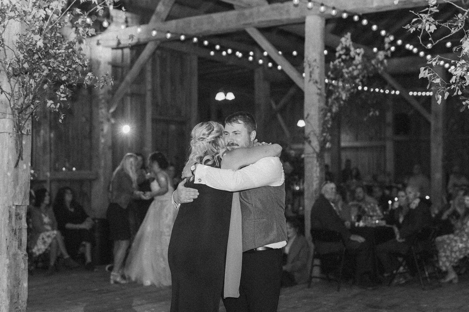 Groom hugging mother during mother son dance after farm weddings