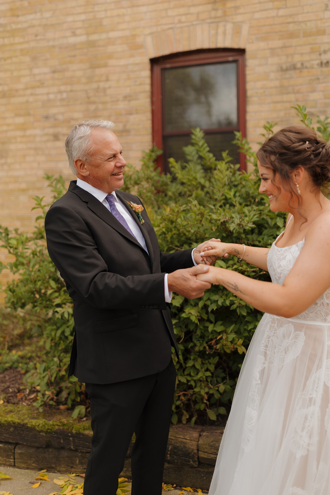 Emotional father-daughter first look outside a rustic building, capturing joyful expressions before the Wisconsin wedding ceremony.
