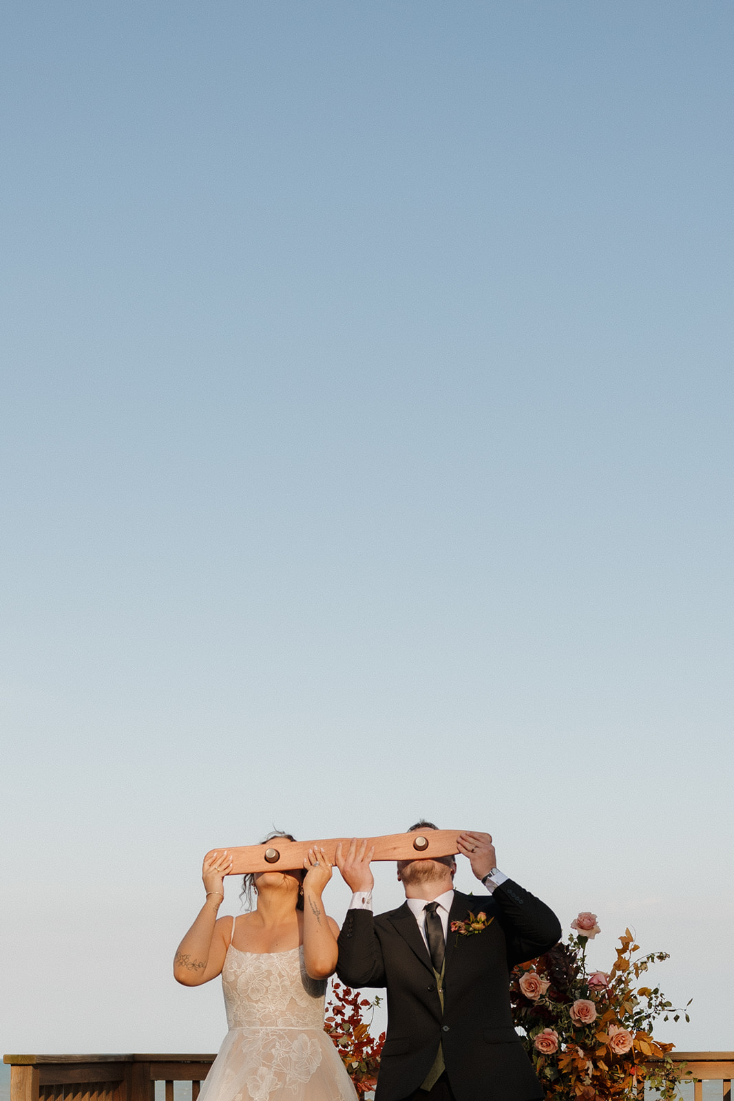 Bride and groom take a celebratory wedding shot with a custom paddle, adding a playful touch to their lakeside Wisconsin wedding.