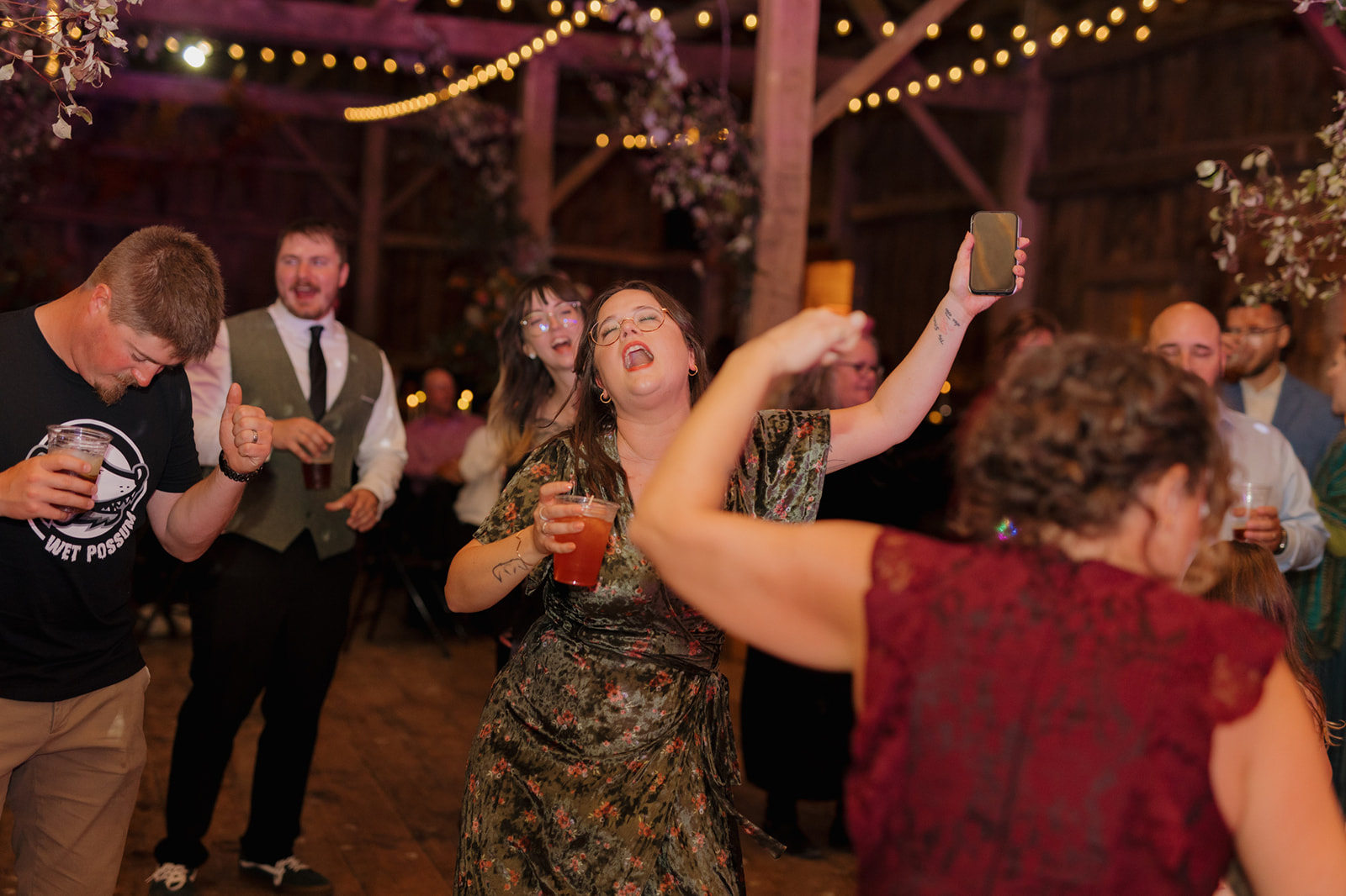 Guests throwing hands in the air to dance and celebrate while holding signature drinks