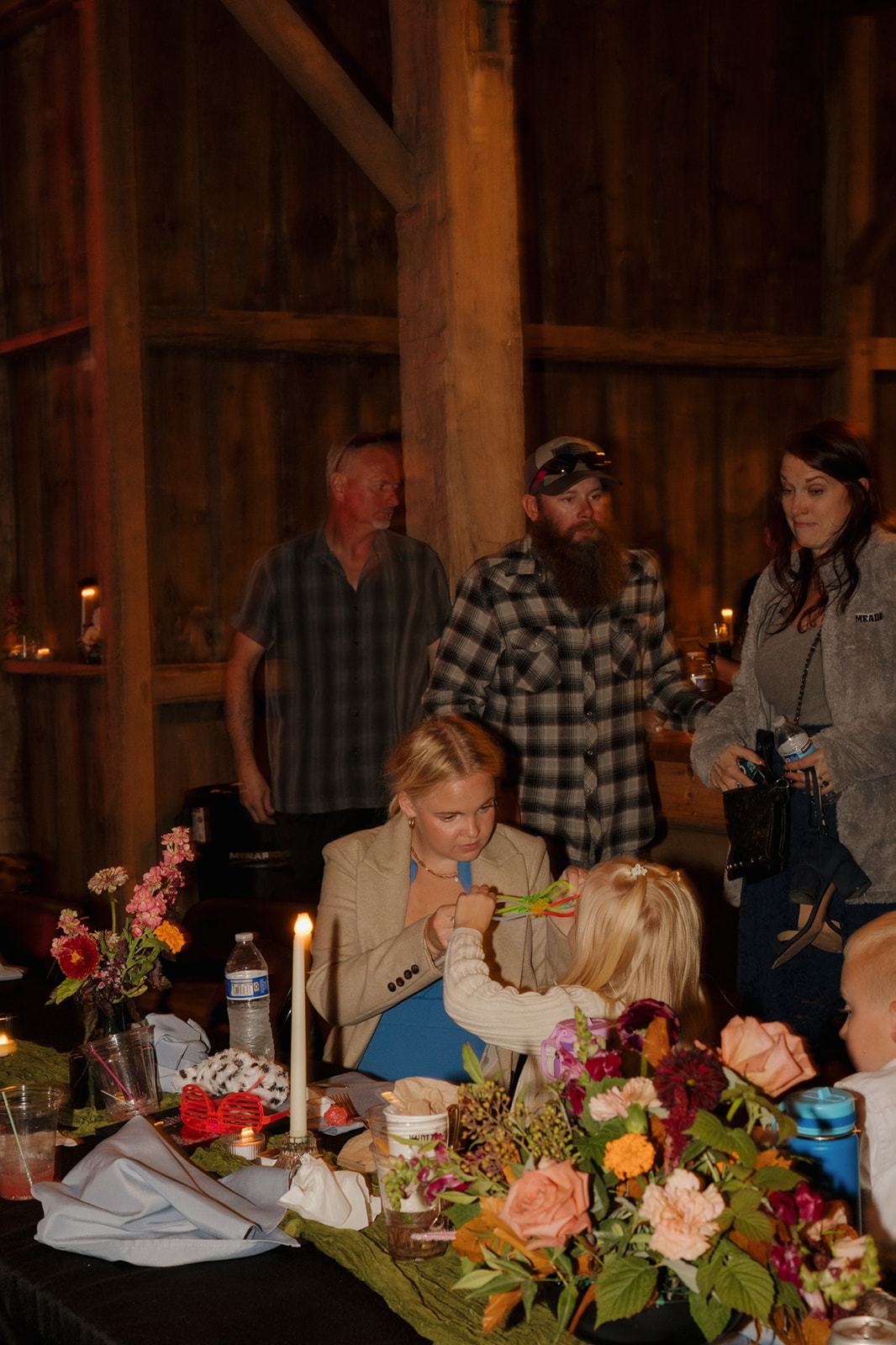Wedding guests celebrating with children at farm wedding reception in barn
