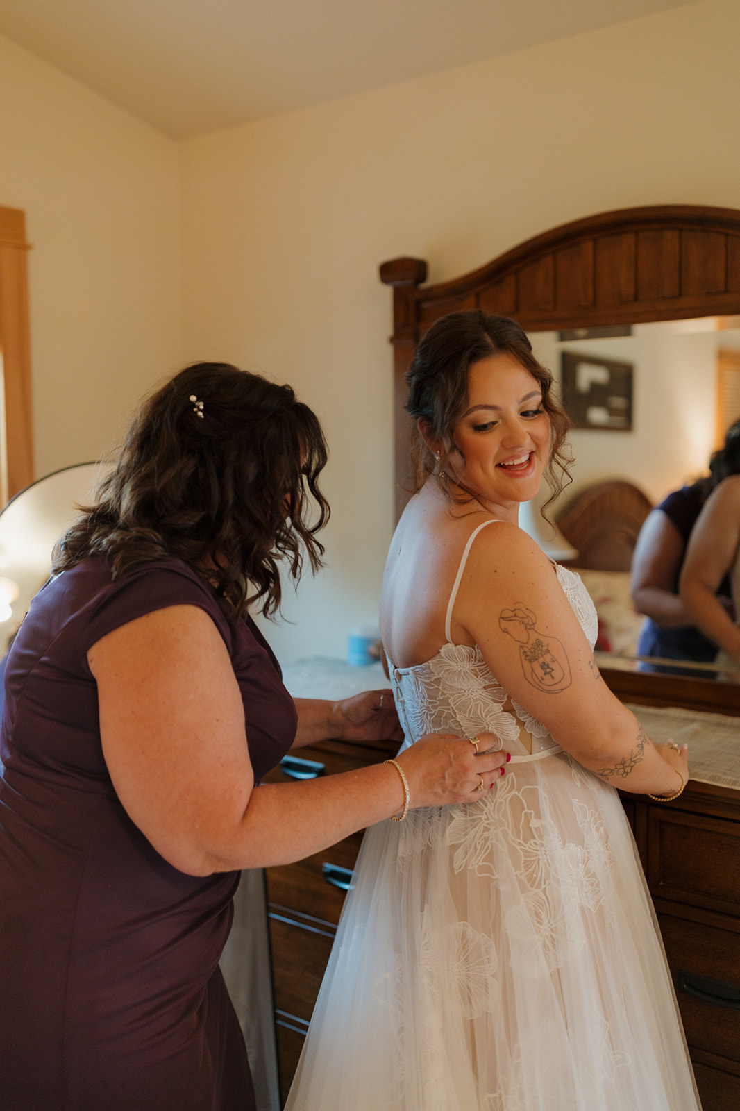 Bride and her mom share a sweet moment while fastening the wedding dress, captured in a warm and personal Wisconsin wedding prep scene.