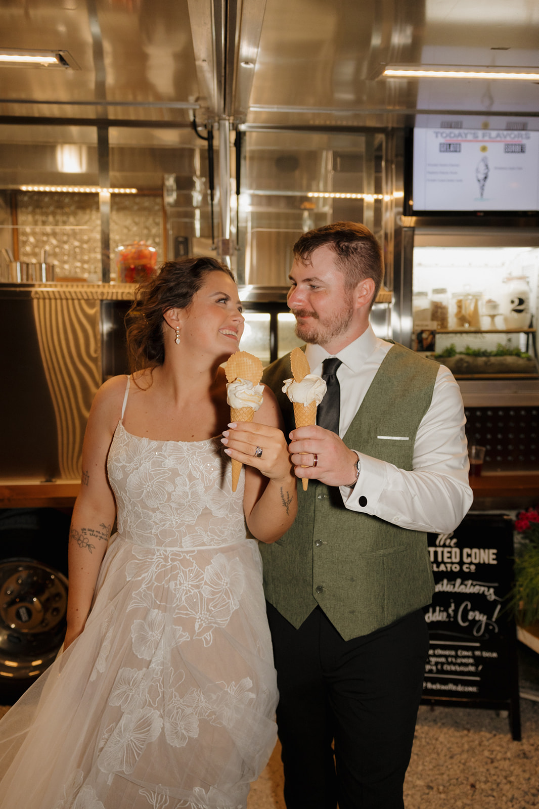 Bride and groom laughing and holding ice cream cones in front of a food truck, enjoying a playful moment during their Wisconsin wedding reception.