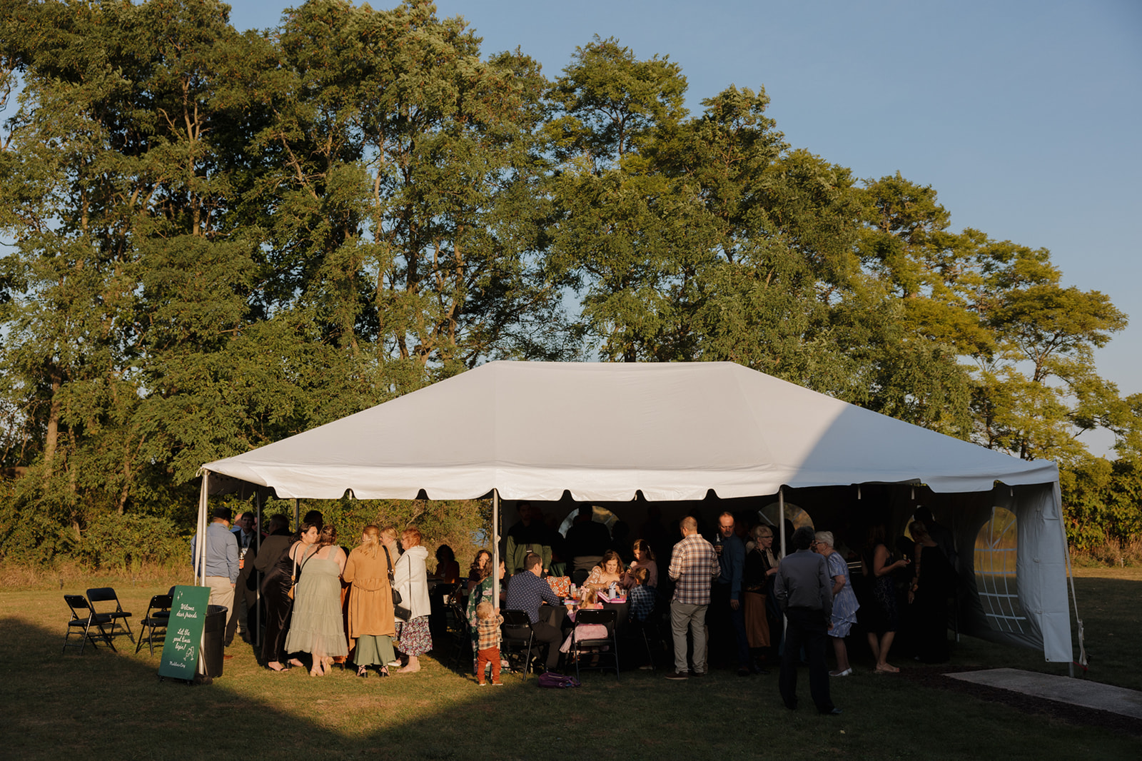 White tent reception set up for wedding guests to enjoy while eating desserts during cocktail hour