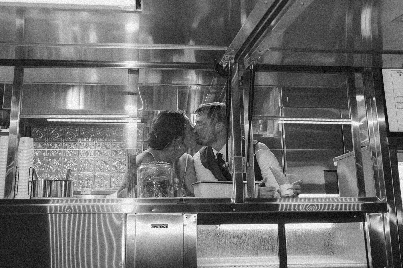 Bride and groom inside food truck kissing before guests arrive to enjoy gelato