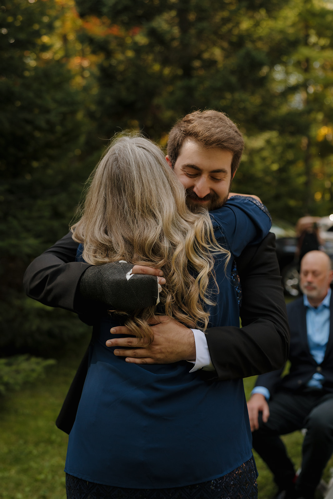 Groom hugging wedding guest tightly during the barn wedding ceremony.