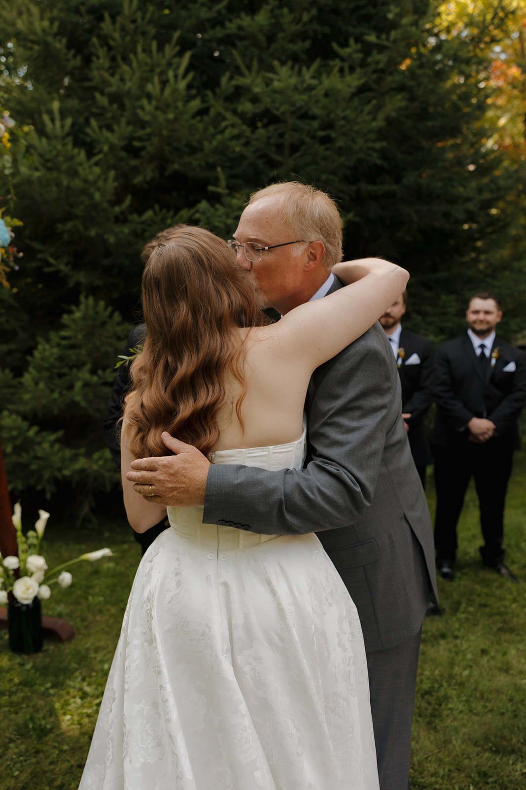 Bride hugging her father after walking down the aisle at a barn wedding ceremony.