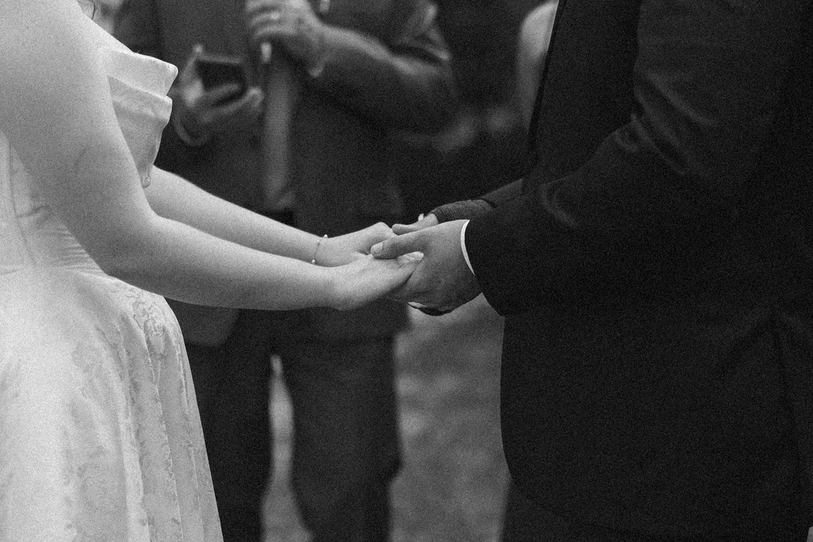 Close-up of bride and groom holding hands during their vows.