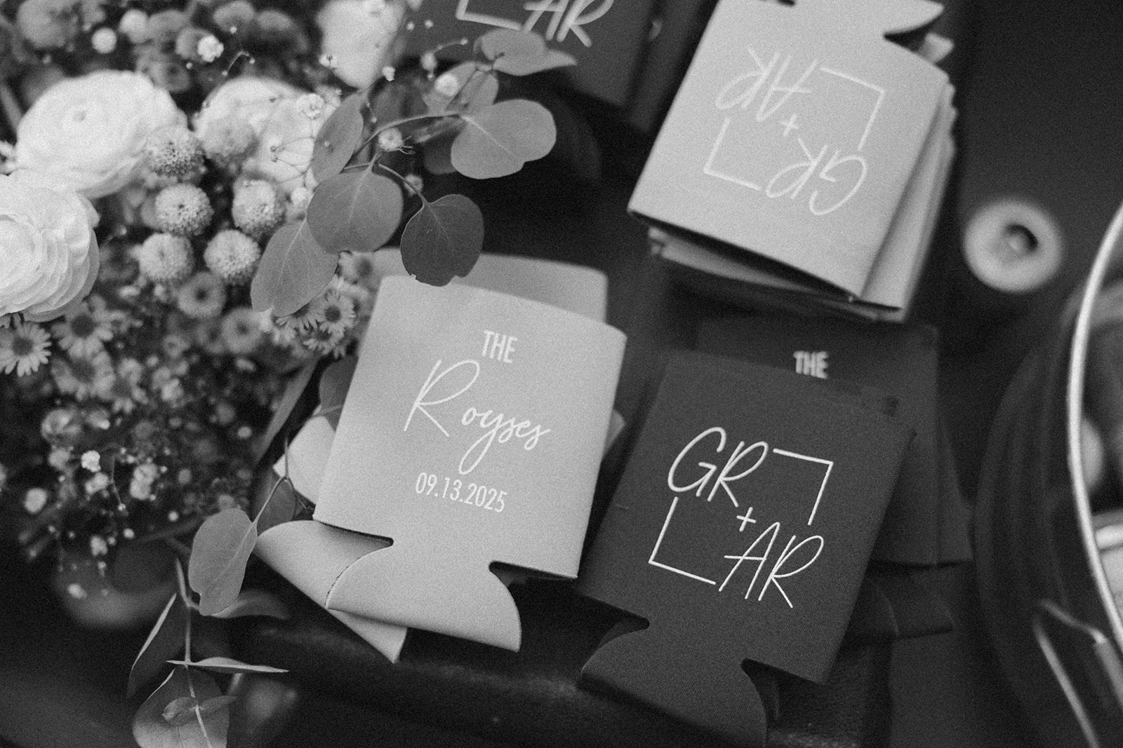 Black and white photo of custom drink koozies with wedding date and couple’s names.