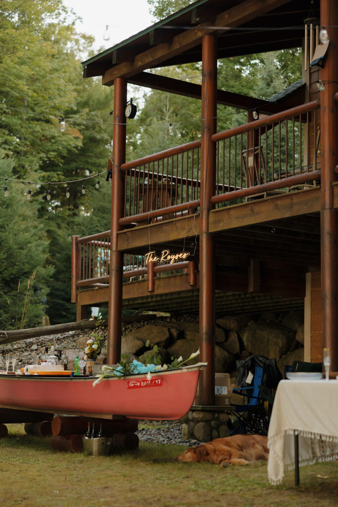 Rustic cabin with canoe bar setup beneath string lights at a barn wedding reception.