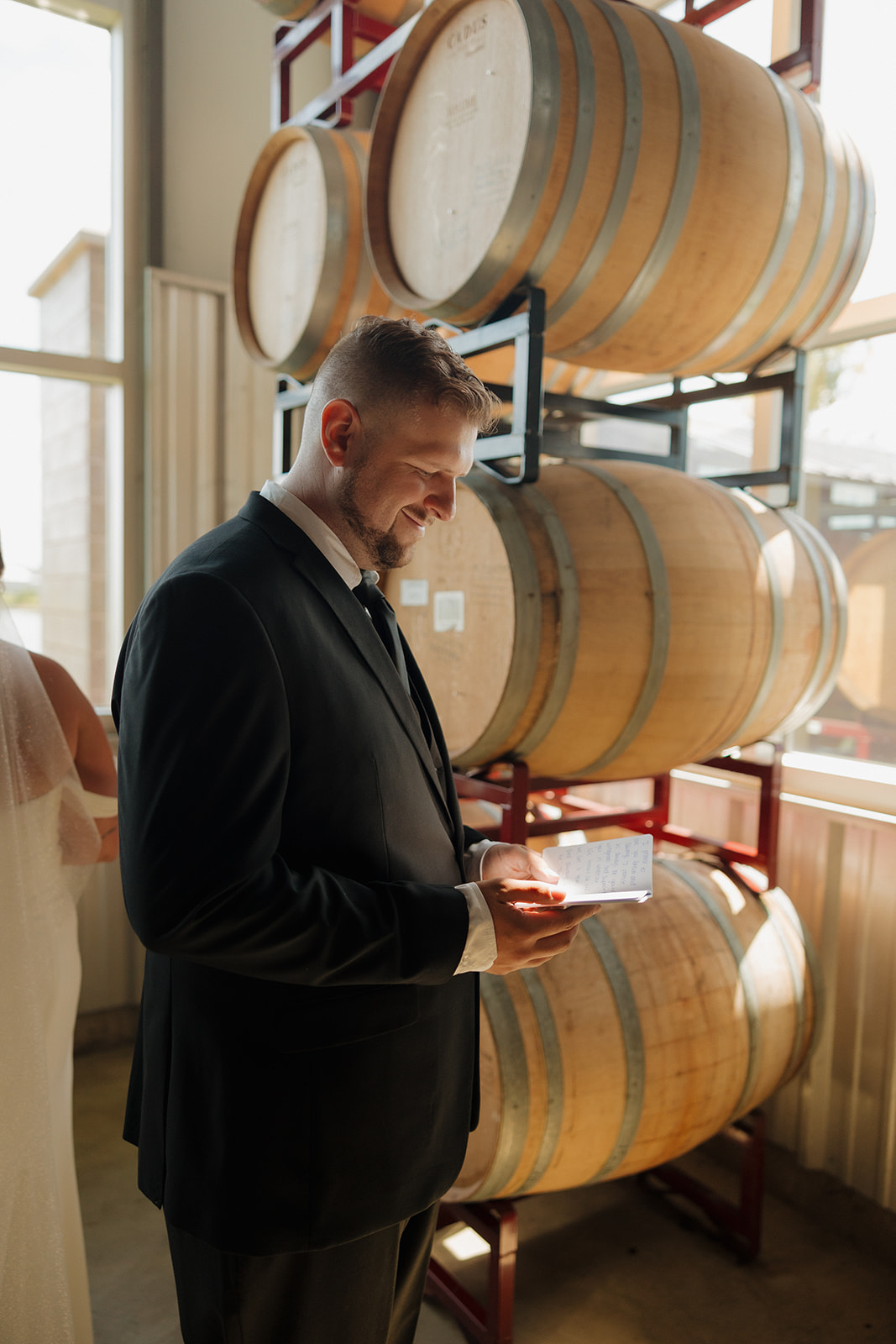Groom smiling as he reads a handwritten note from his bride during their emotional first touch at a Wisconsin brewery wedding.