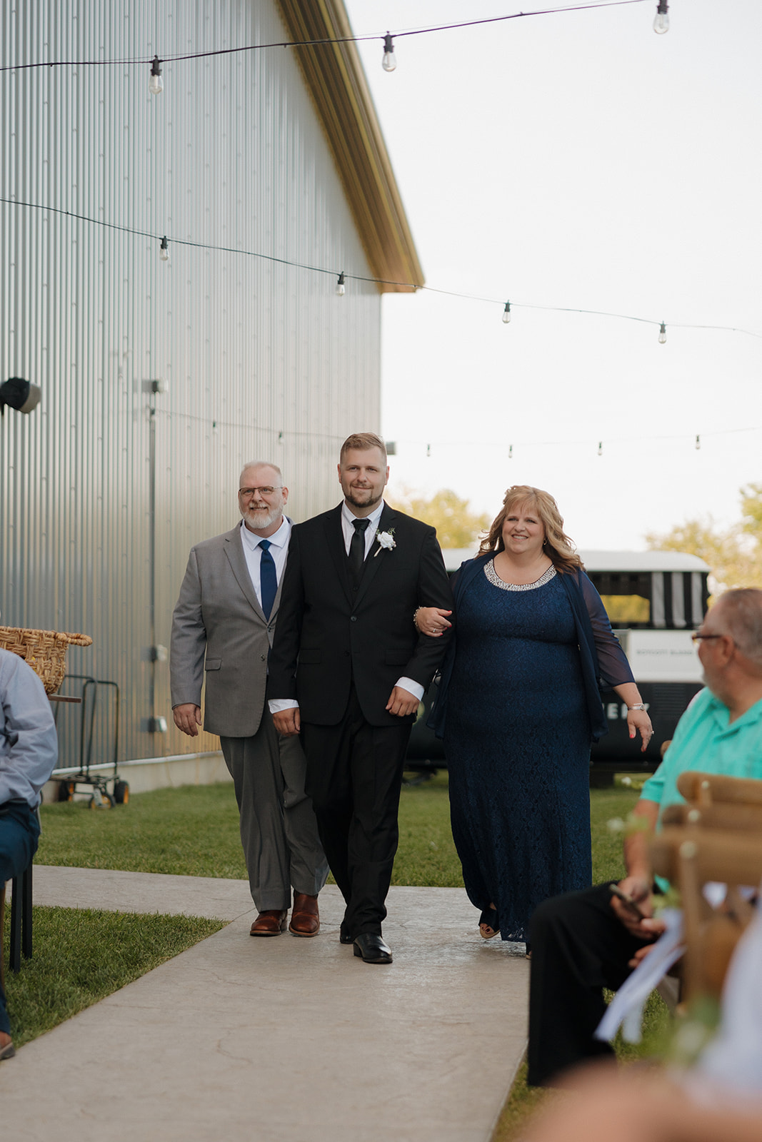 Groom walks down the aisle flanked by both parents before the ceremony begins at a Wisconsin brewery venue.