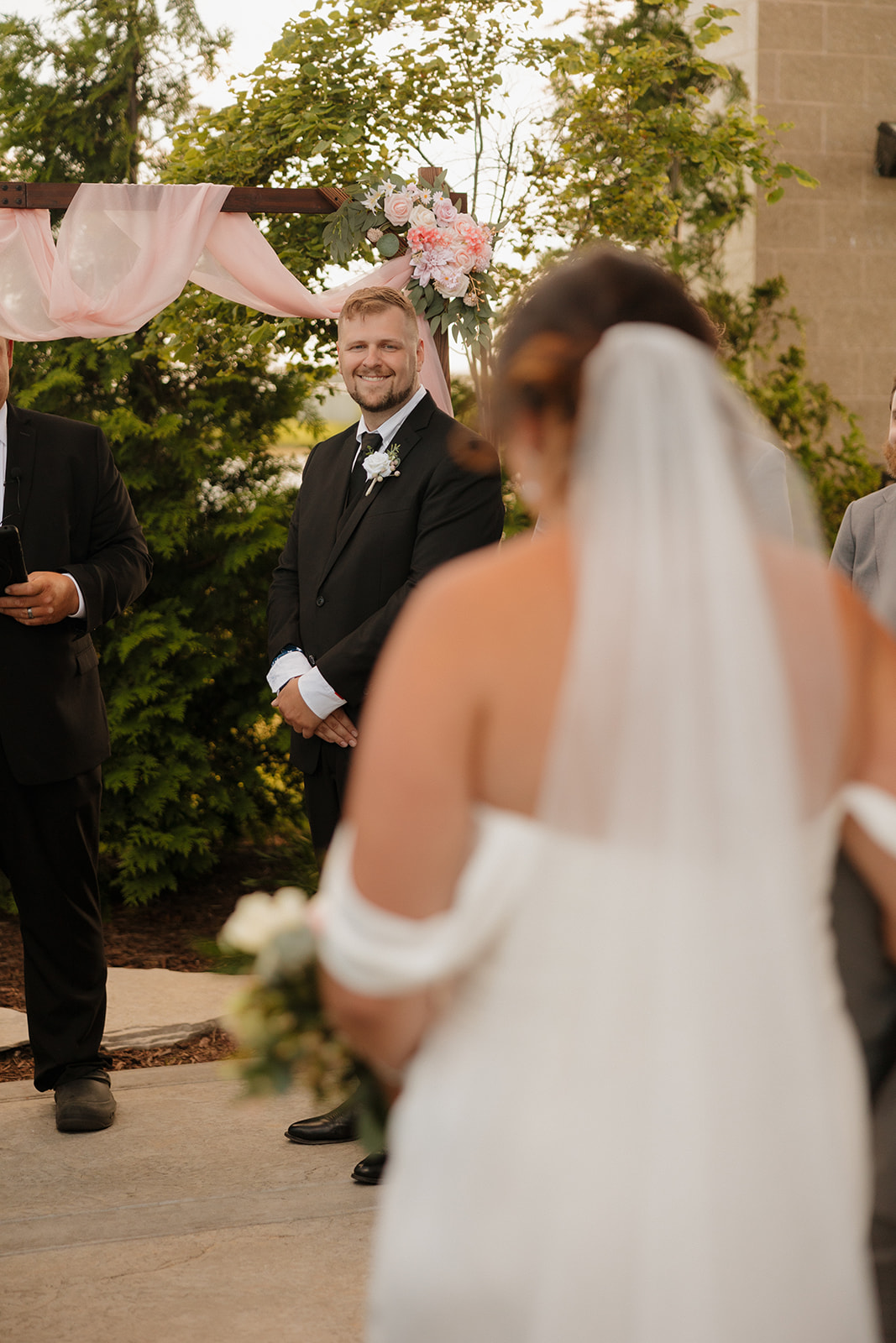 Groom beaming with emotion as he sees his bride walking down the aisle at their Wisconsin brewery wedding.