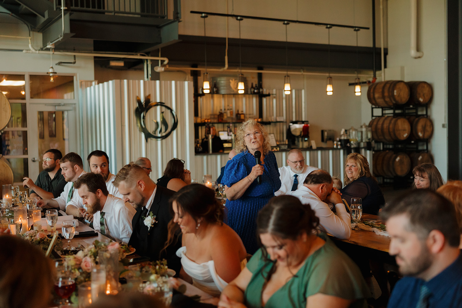 A family member gives a heartfelt toast during the brewery reception as guests laugh and tear up at the long farmhouse tables—classic Wisconsin brewery wedding vibes.