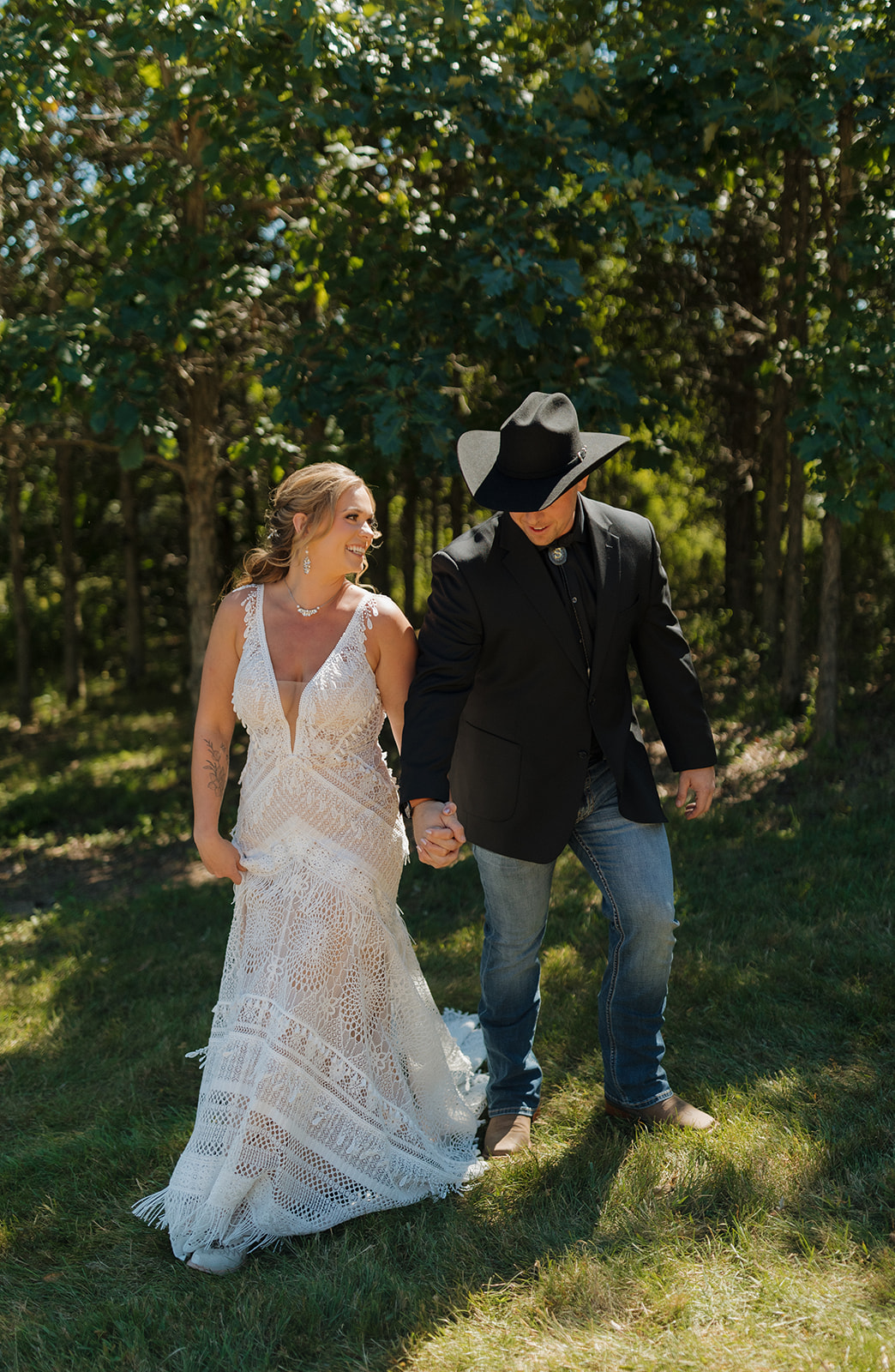 Bride and groom walking hand in hand bumping hips while walking together after backyard wedding