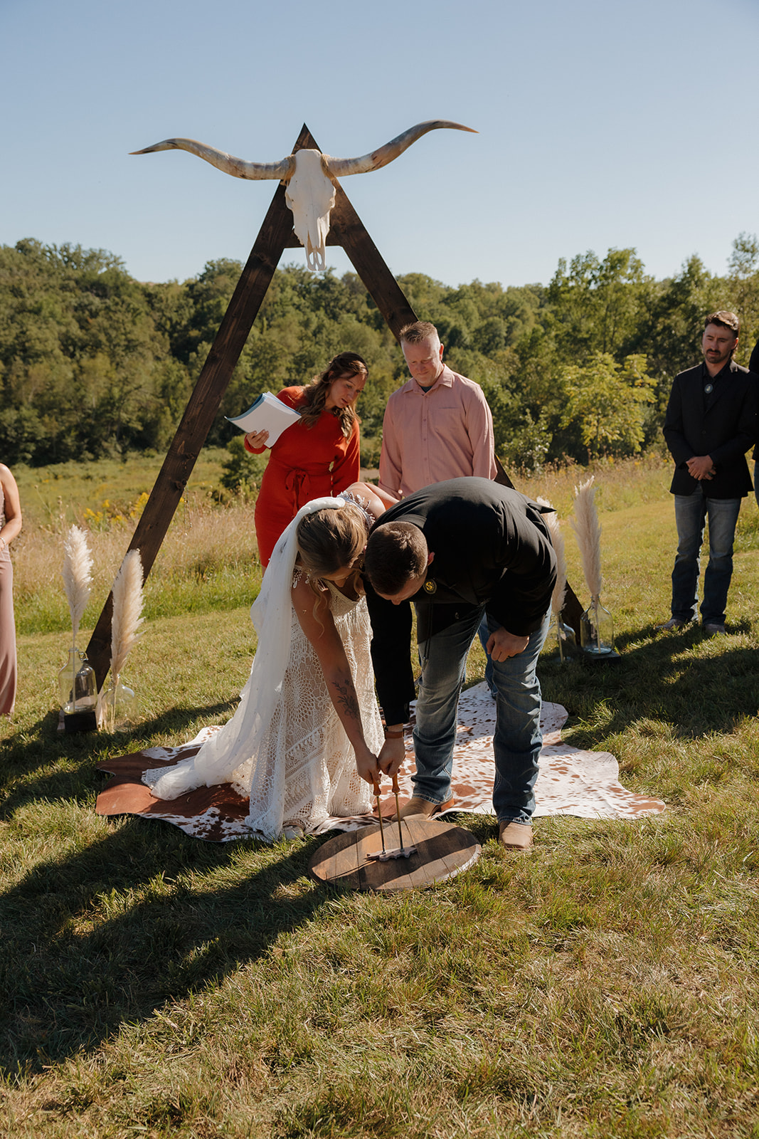 Newly married couple brand piece of leather together after outdoor ceremony