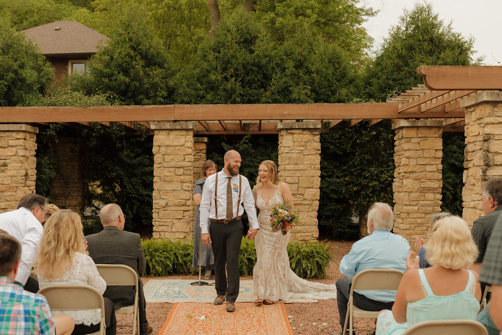 Bride and groom hold hands and walk out of outdoor wedding ceremony hand in hand