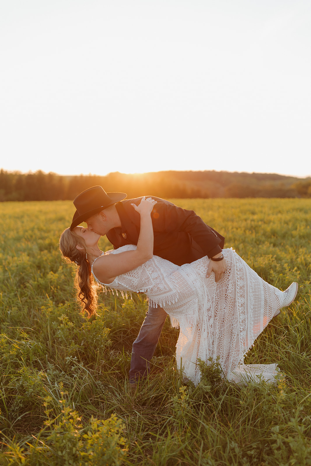 Groom dip kisses bride at sunset after intimate outdoor wedding in Wisconsin