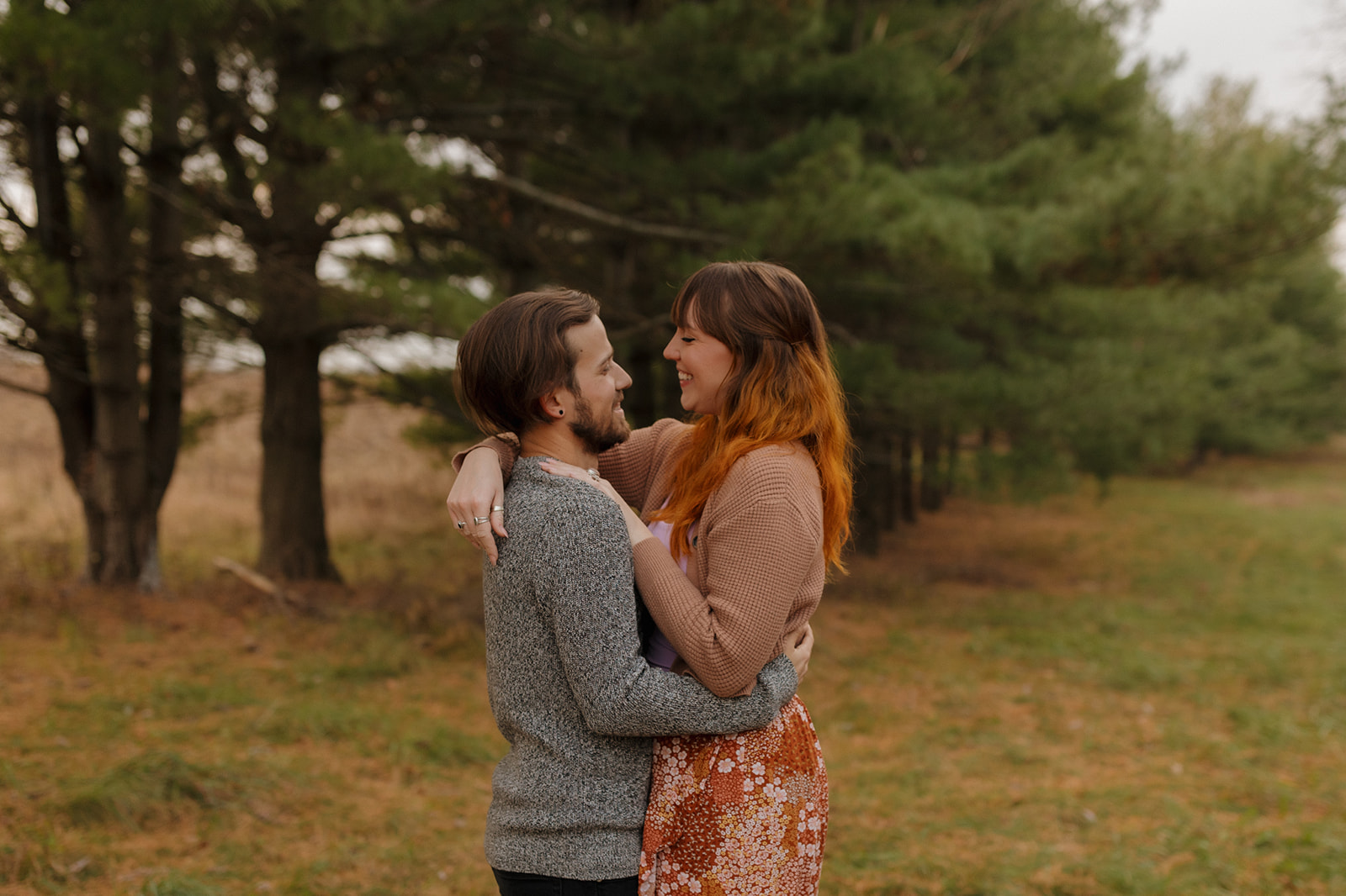 Happy couple in a beautiful forest during their engagement shoot, taken by a Madison WI wedding photographer.