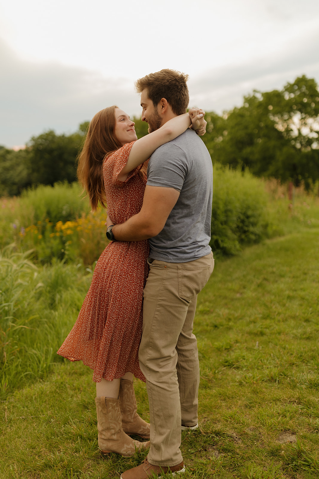 A couple poses in a beautiful field for engagement photos, taken by a Madison WI wedding photographer, celebrating their love.