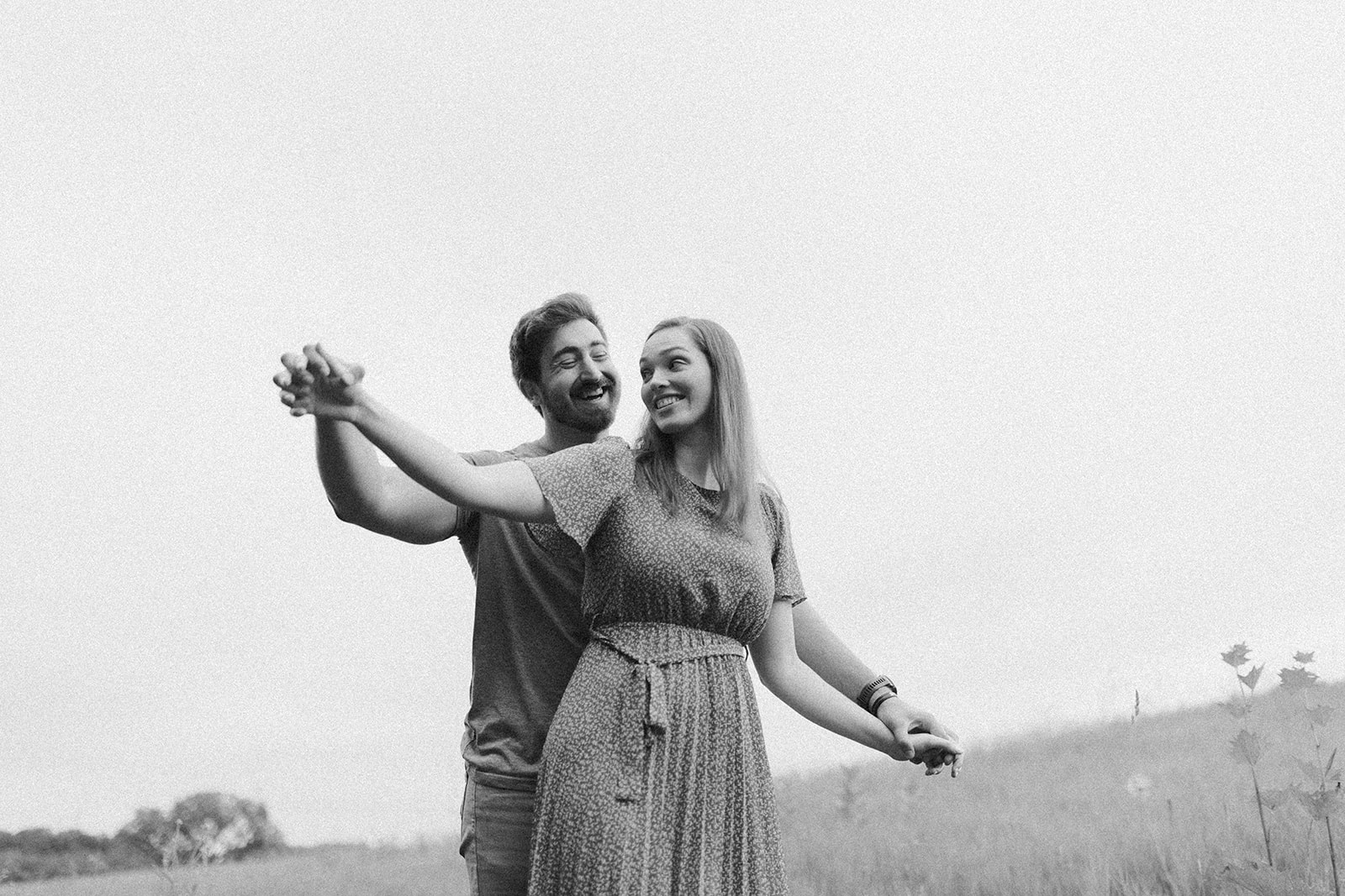 A couple stands together in a vibrant field, hands clasped, sharing a moment of connection captured by madison wi wedding photographer