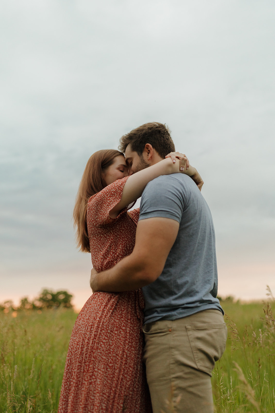 Engaged couple embracing placing foreheads together during outdoor engagement photos captured by madison wi wedding photographer