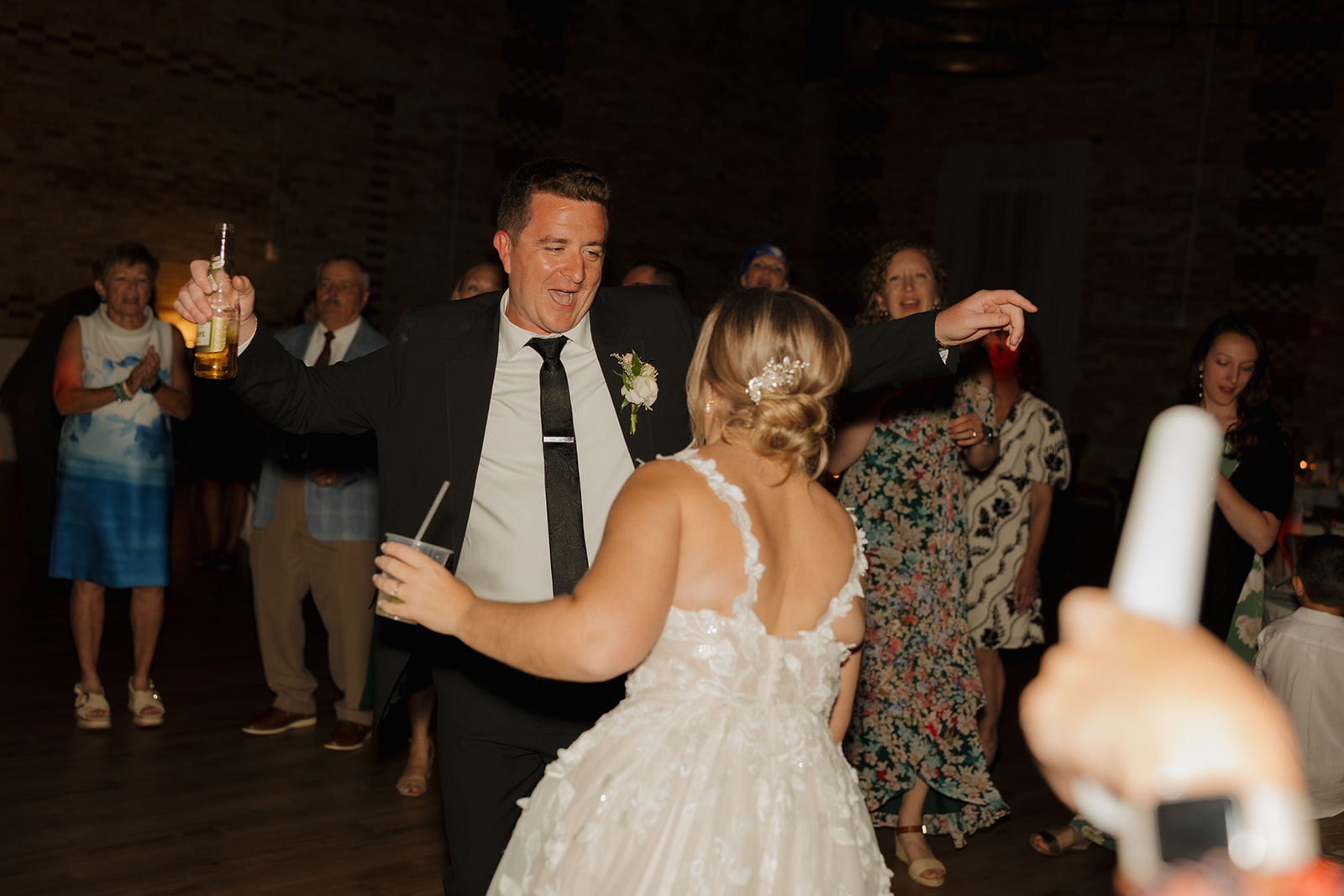 Bride and groom dancing on the dance floor celebrating marriage with drinks in their hands laughing together